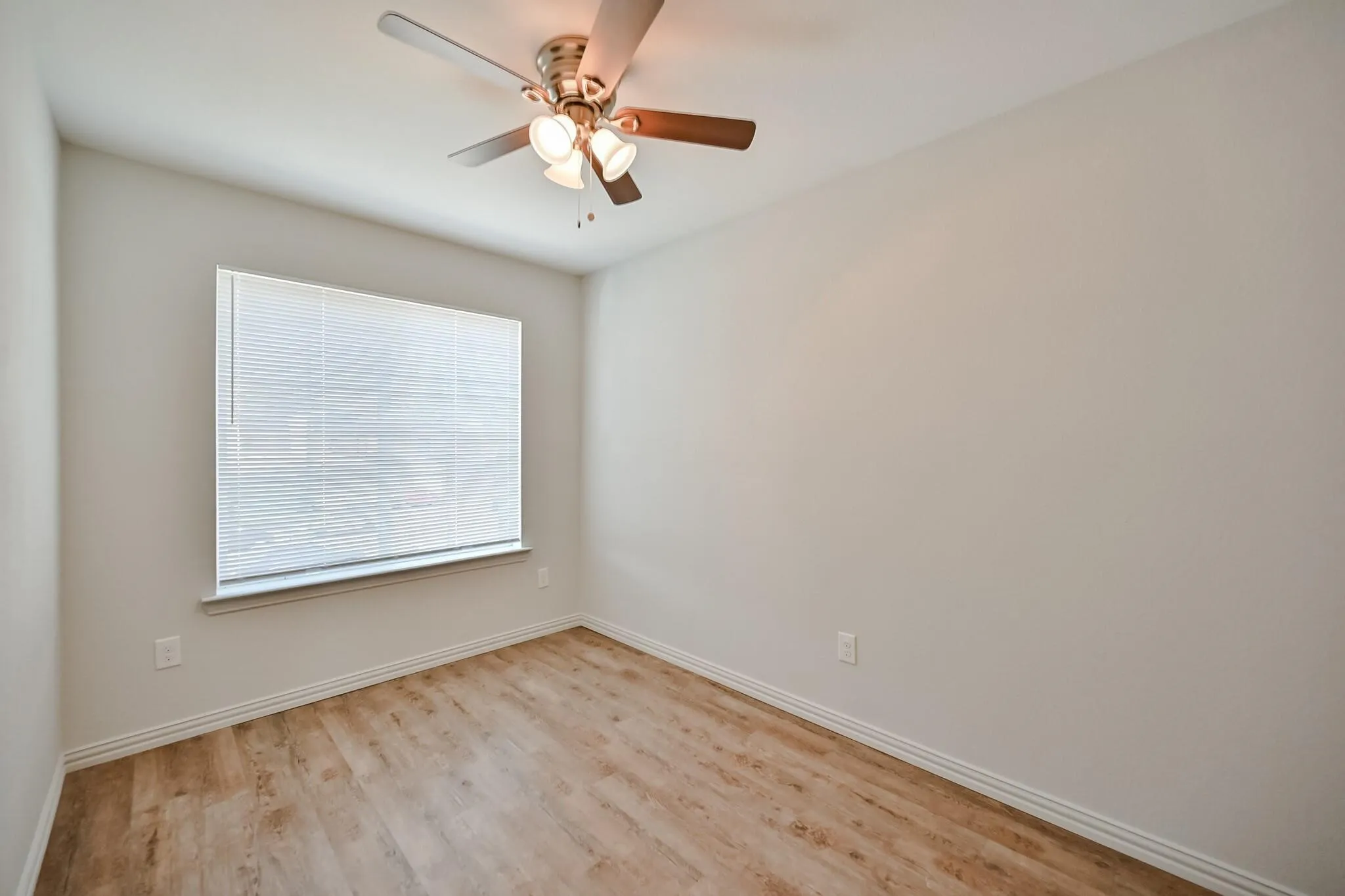 Empty room with light wood finished floors and ceiling fan