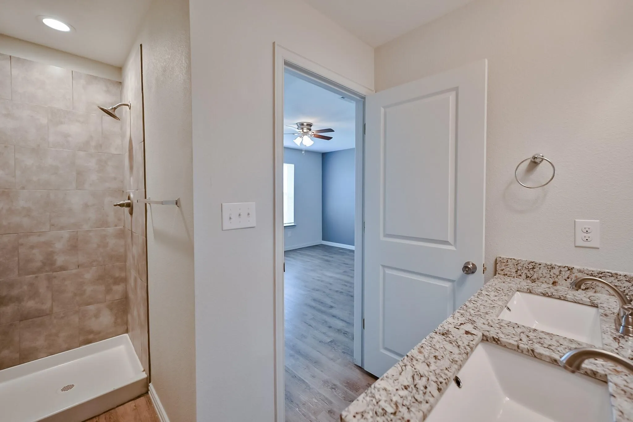 Bathroom with a shower stall, light wood-type flooring, and double vanity