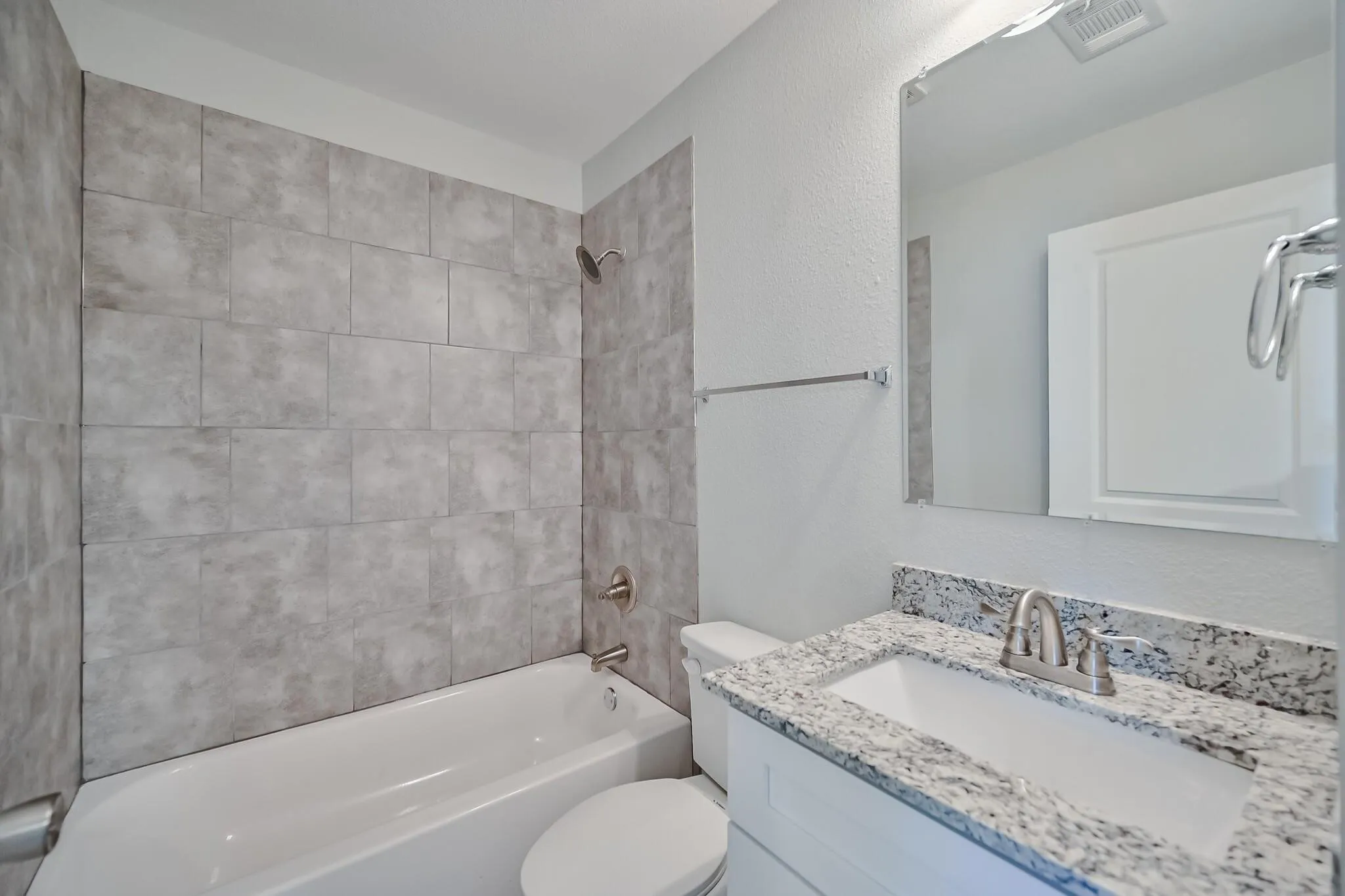 Bathroom with tub / shower combination, vanity, and a textured wall