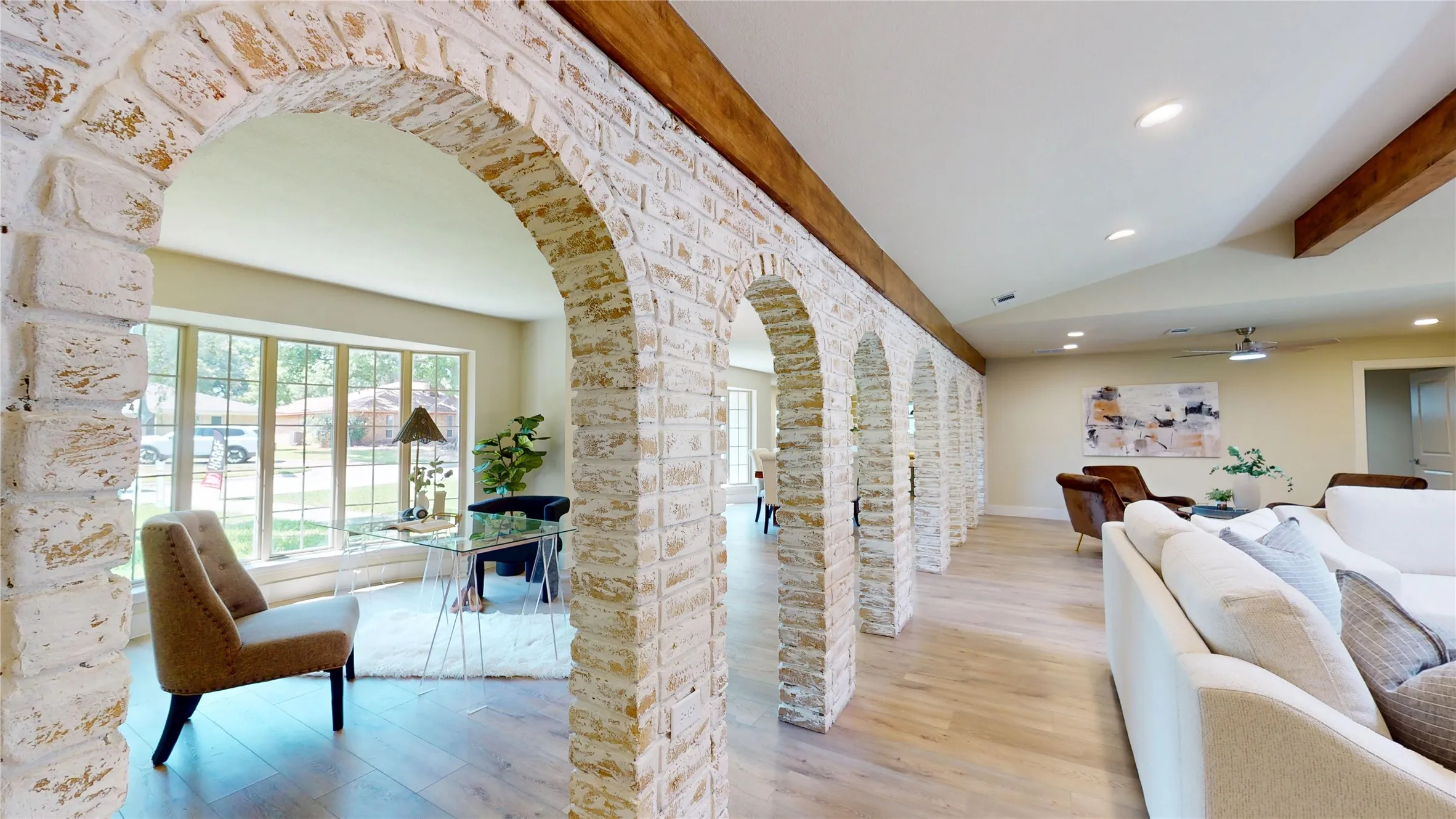 Arched brick passageway with exposed wood beams, wood-finish flooring, recessed lighting, and large windows