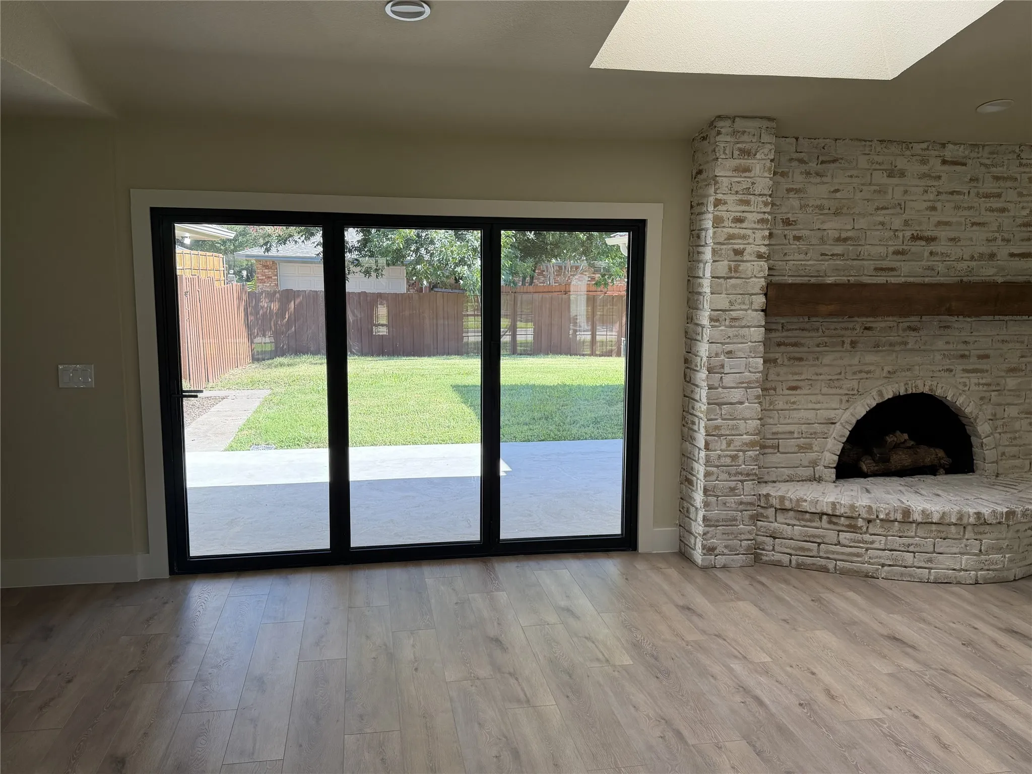 Wood-finish flooring, brick fireplace with German Schmear  brick, exposed wood mantel, skylight, and large accordion glass doors, closed