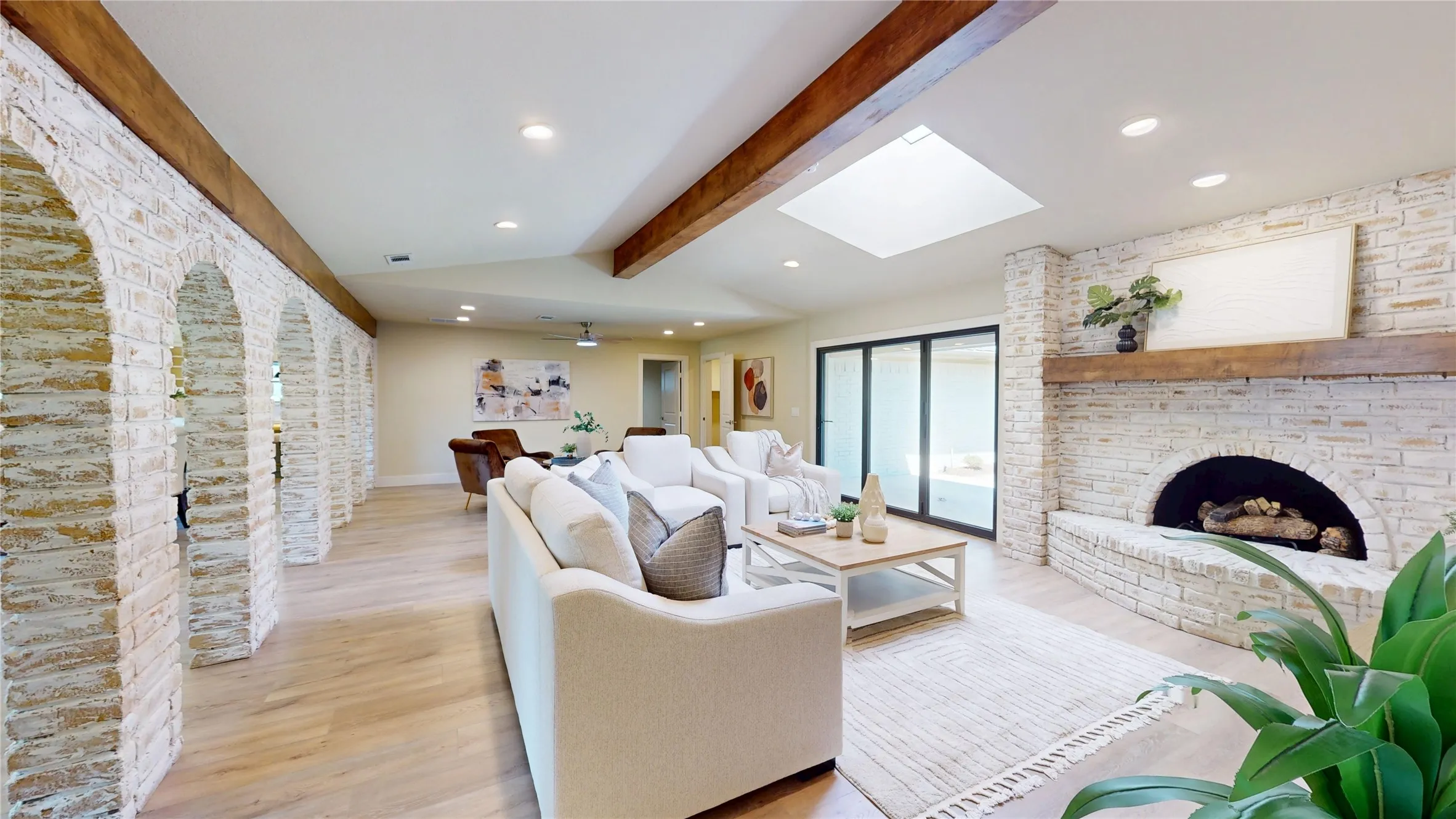 Spacious living area featuring wood-finish flooring, exposed wood beams, and a skylight