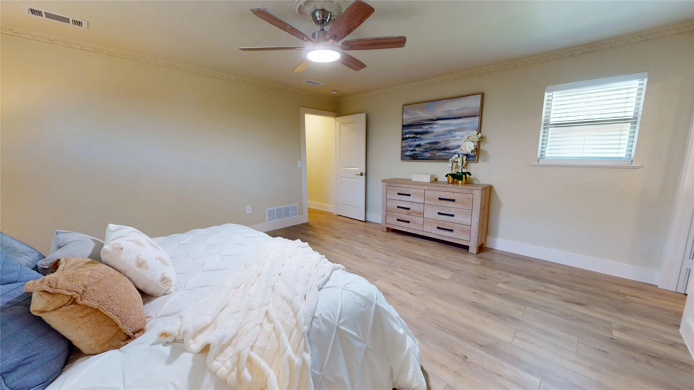 Wood-finish flooring, single window with blinds, ceiling fan with integrated lighting, crown molding, and white trim