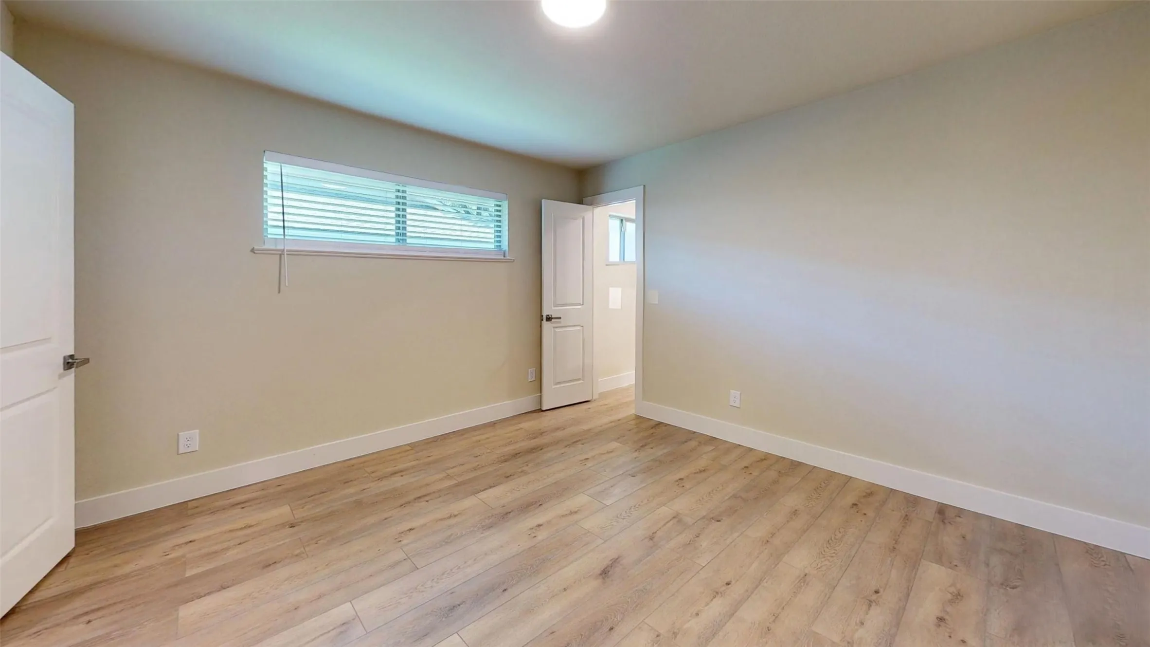 Wood-finish flooring, neutral wall tones, and a single window with blinds