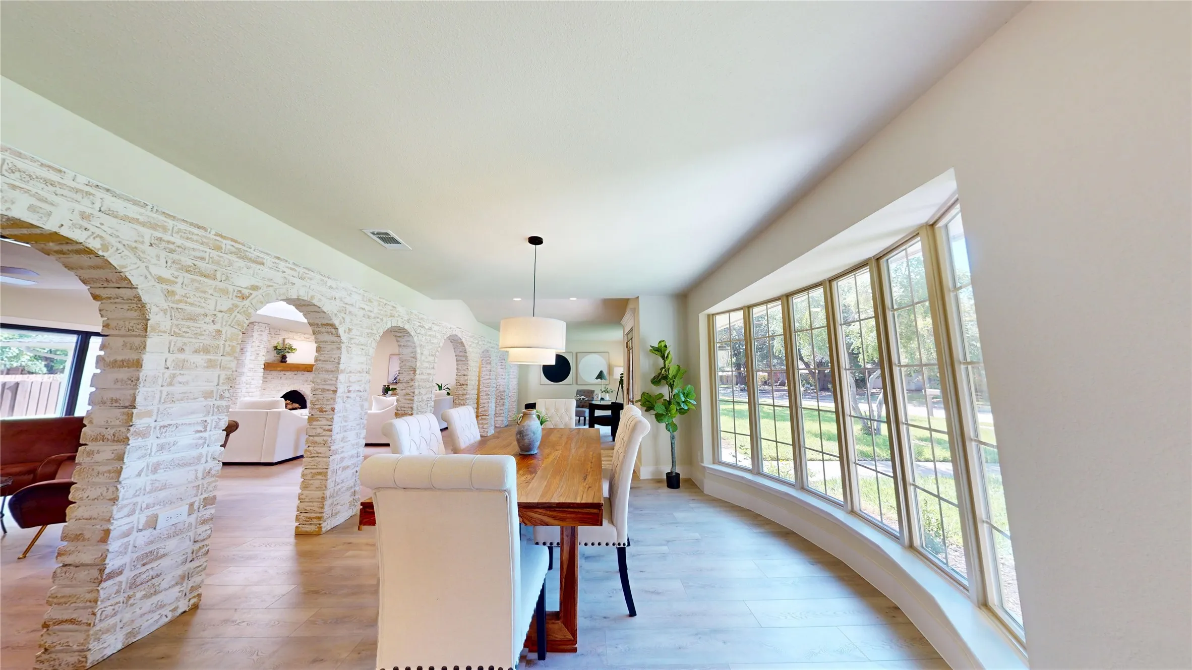 Curved bay window, arched German Schmear brick entryway, wood-finish flooring, recessed lighting, and a contemporary pendant fixture
