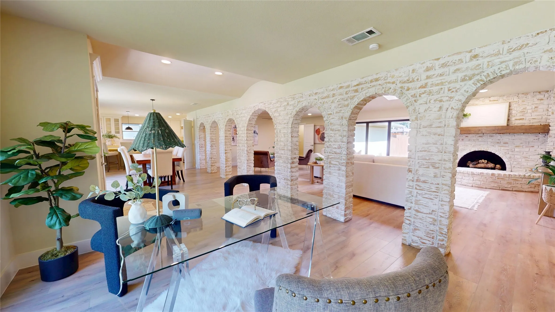 German Schmear brick archways, wood-finish flooring, a recessed fireplace with a wood mantle, and an open layout