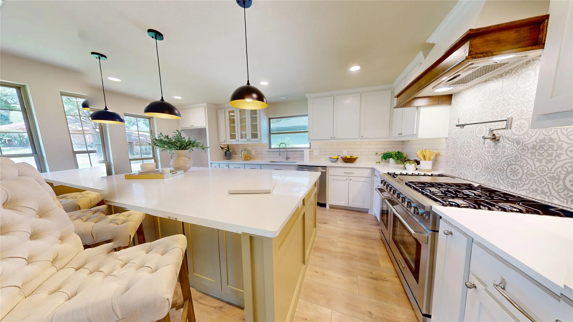 Kitchen featuring a large central island, pendant lighting, professional-grade range, patterned tile backsplash, and white cabinetry