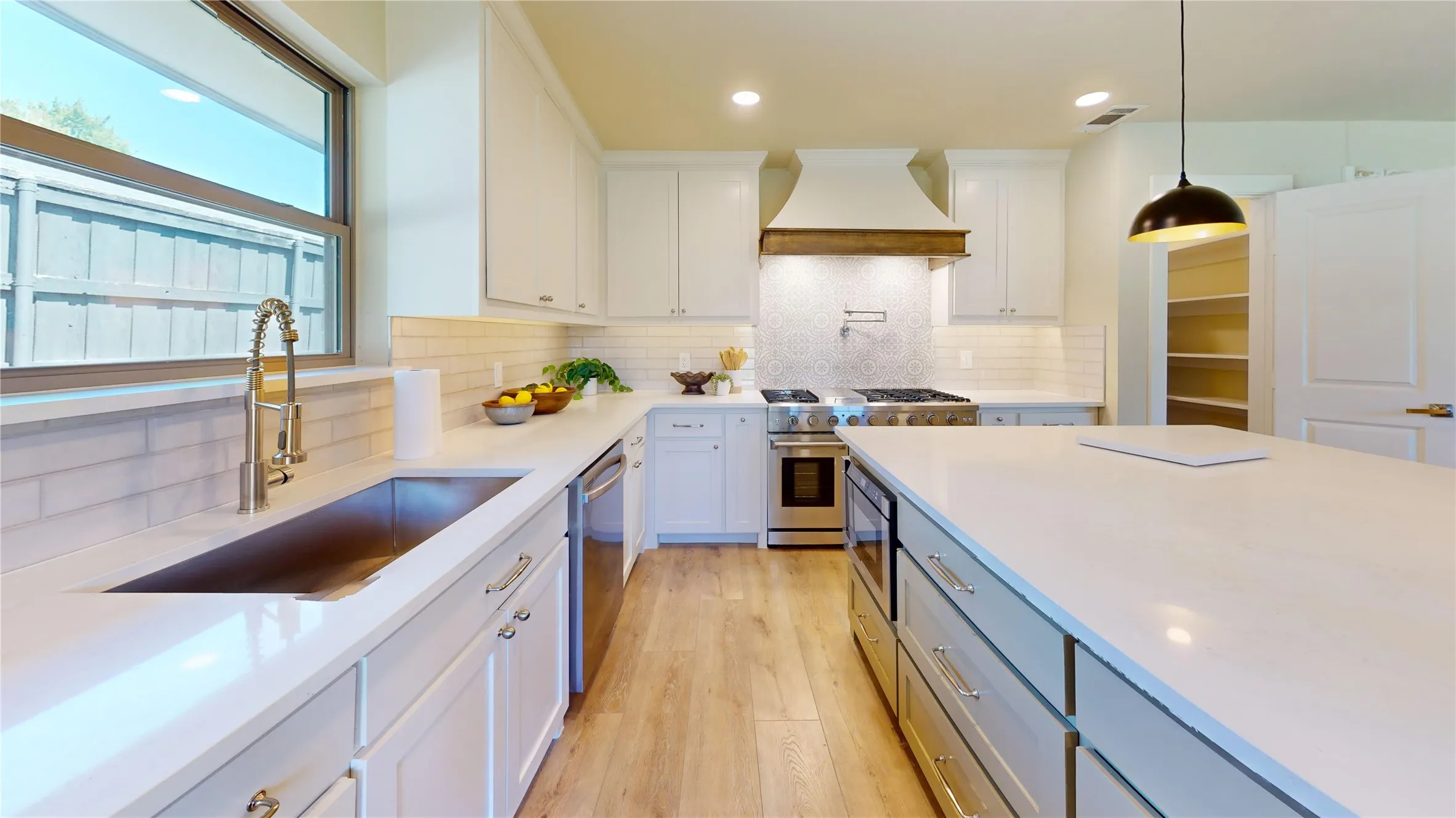 Kitchen featuring white cabinetry, light countertops, stainless steel appliances, and wood-finish flooring