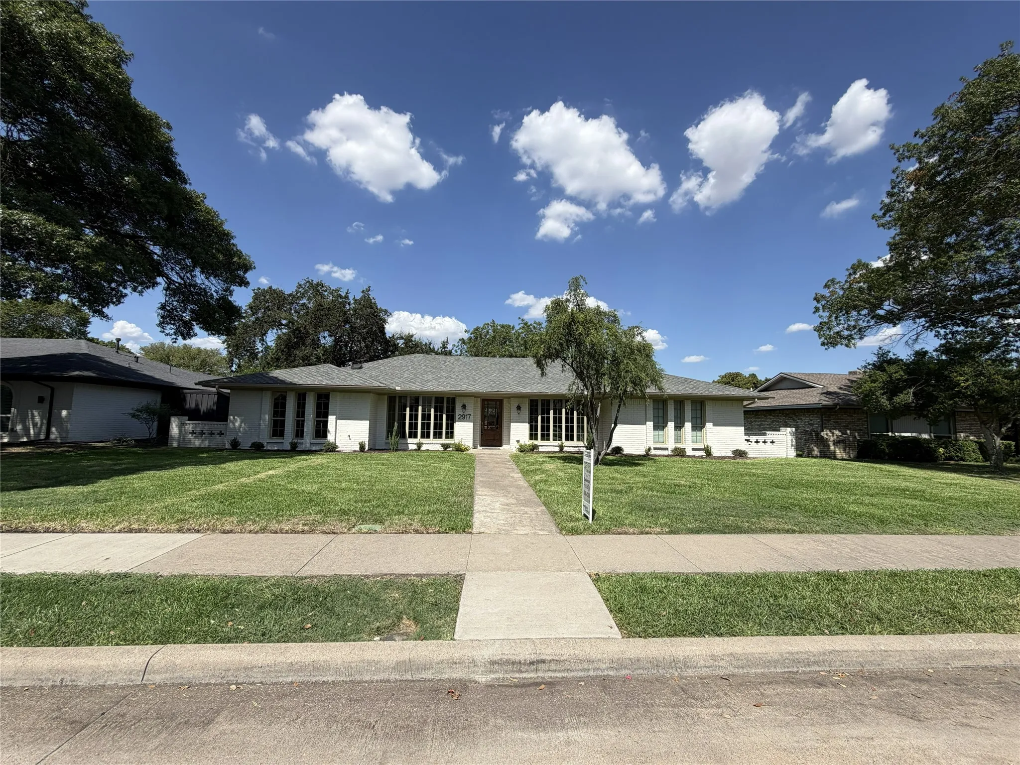 Single-story exterior with a gray shingle roof, white siding, and a prominent front walkway