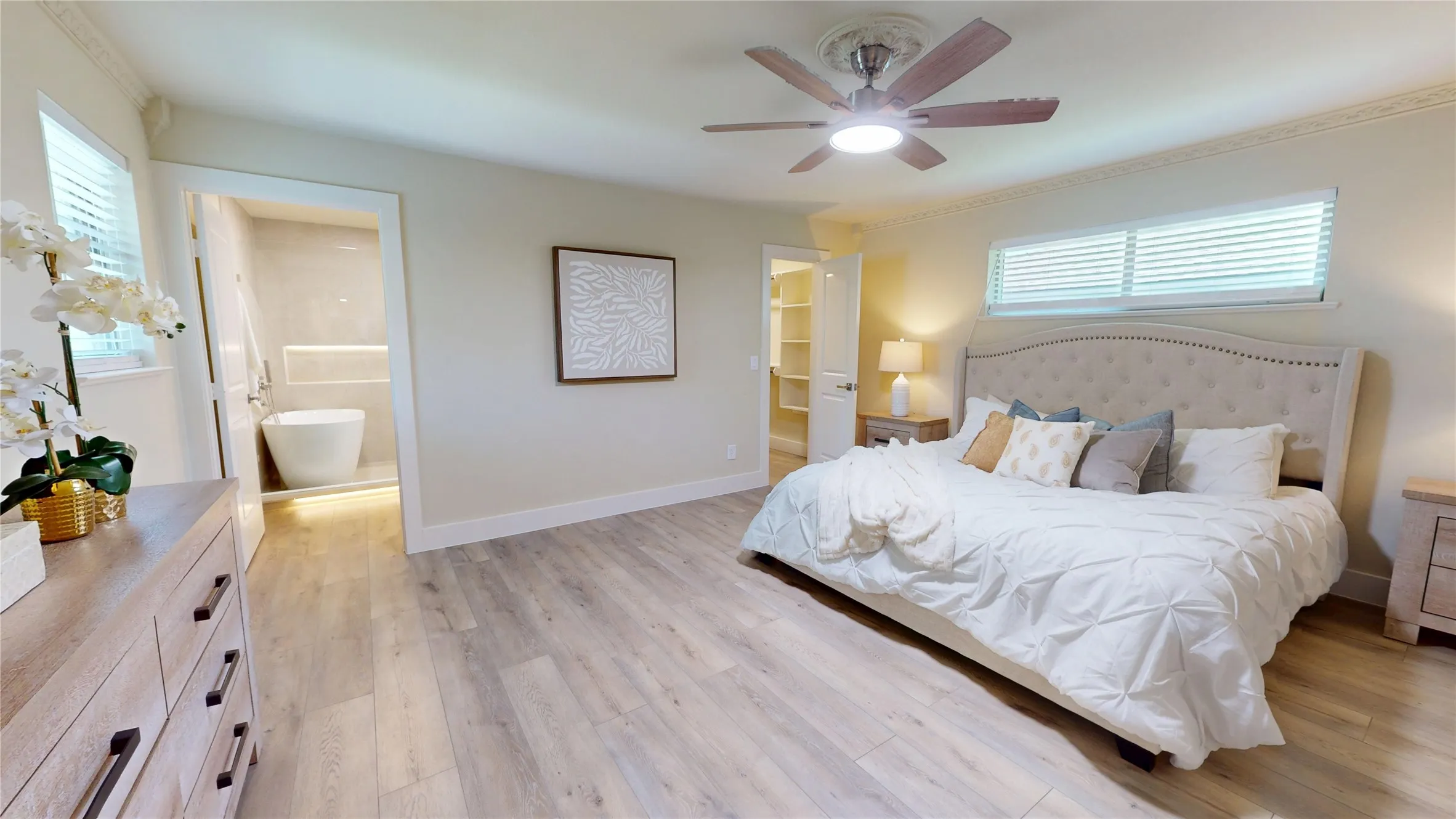 Wood-finish flooring, crown molding, ceiling fan with integrated lighting, recessed lighting, and a freestanding soaking tub