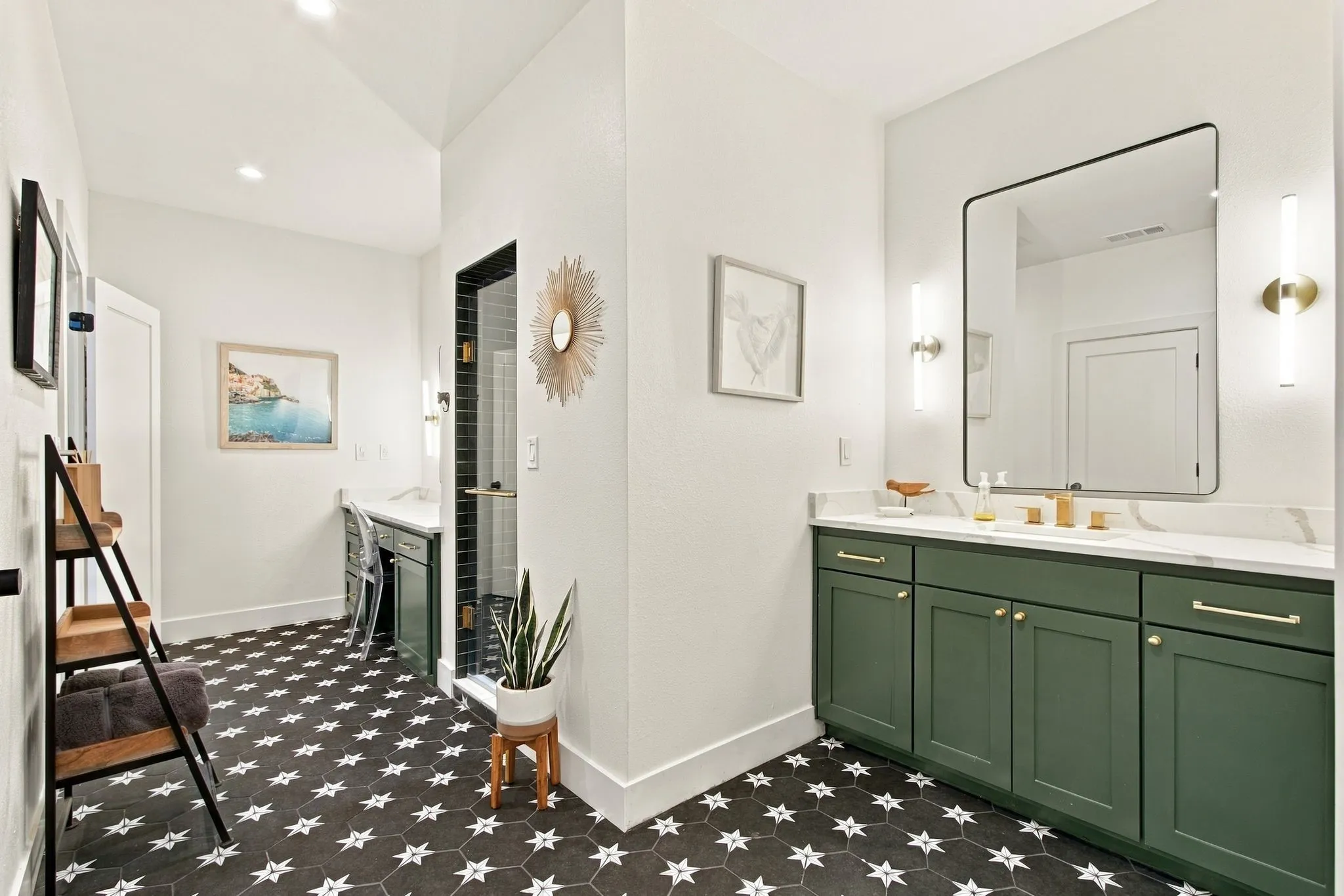 Hexagonal floor tiles with star accents, vanity with green cabinetry, double sinks, modern wall-mounted light fixtures, and a frameless shower with dark subway tile