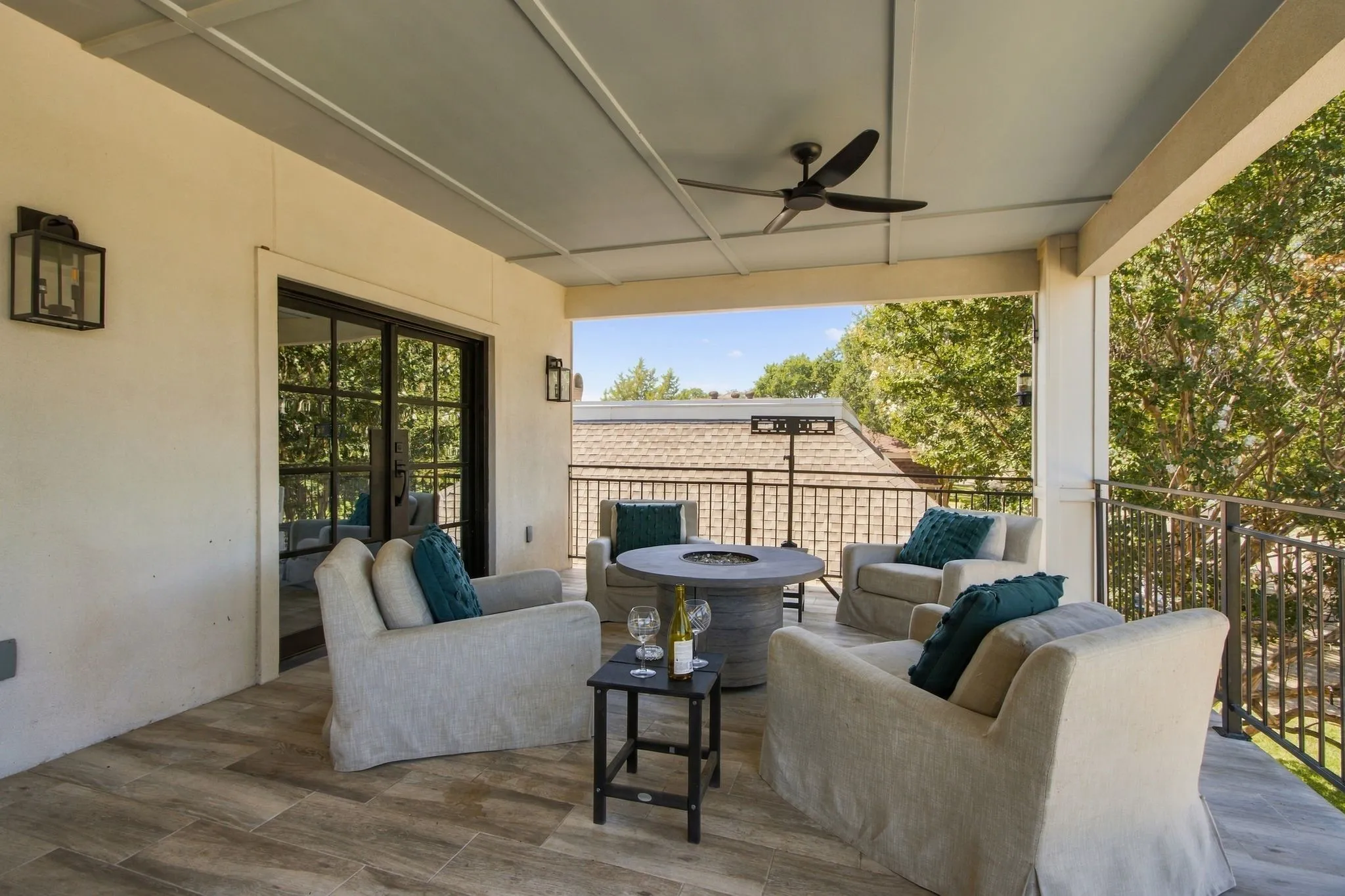 Covered balcony featuring wood-finish flooring, a ceiling fan, and black metal railings