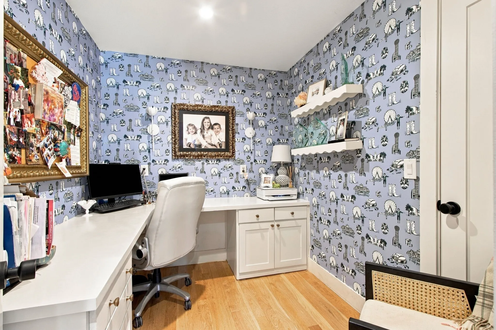 Built-in desk with cabinetry, wood-finish flooring, recessed lighting, white interior door with matte black hardware, and two white floating shelves