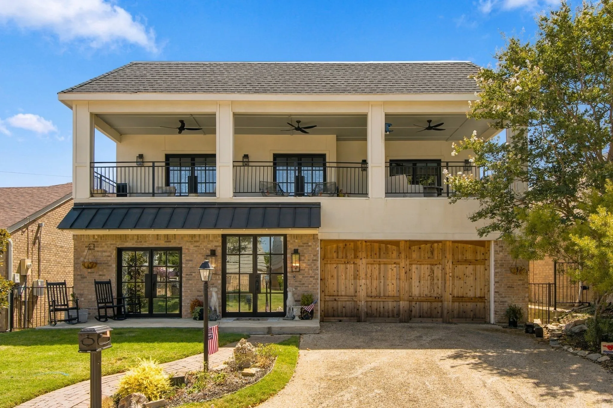 Brick exterior with a second-story covered balcony featuring black railings and ceiling fans