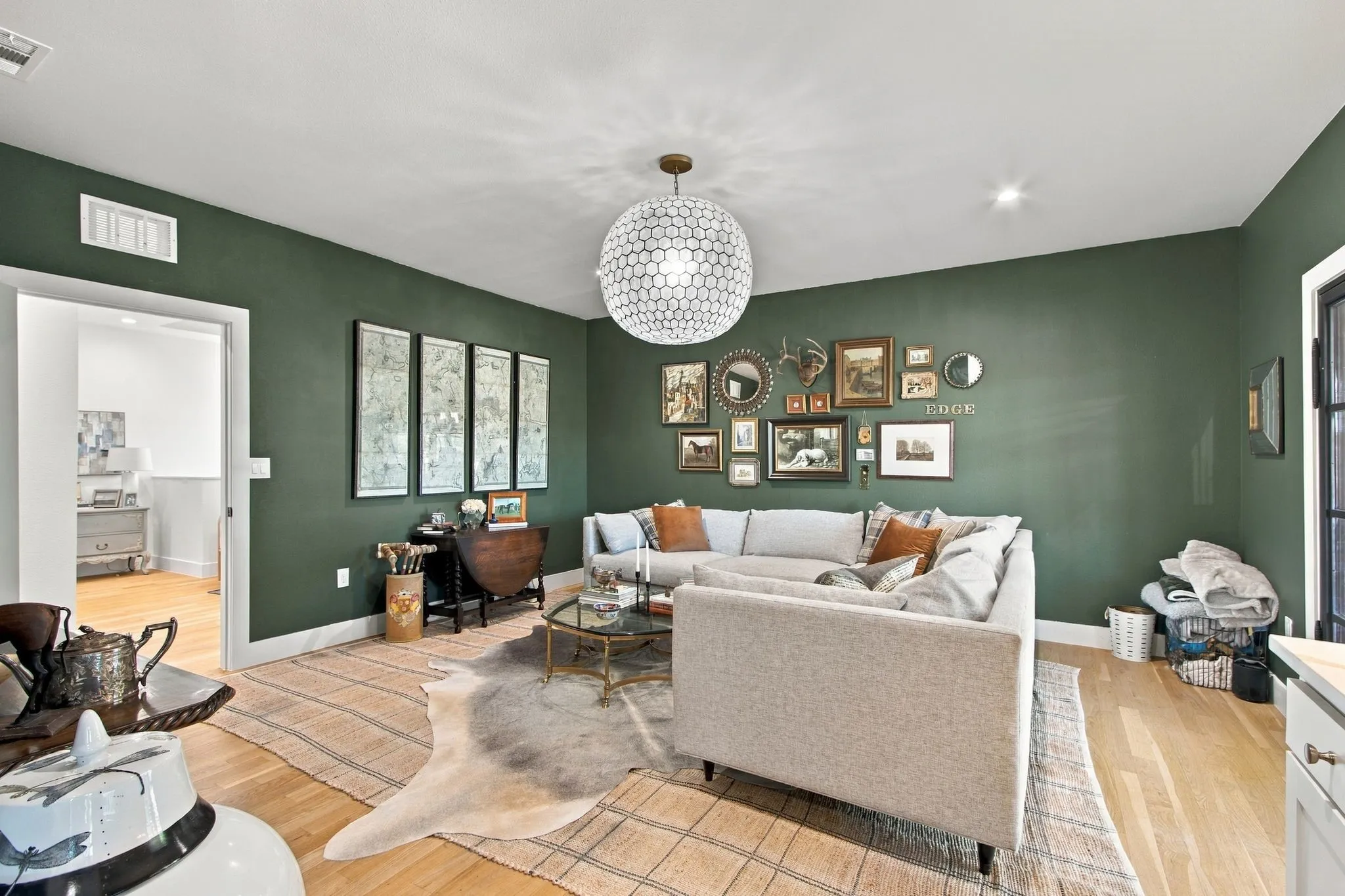 Light wood-finish flooring, recessed lighting, and a modern ceiling fixture illuminate this space with green walls