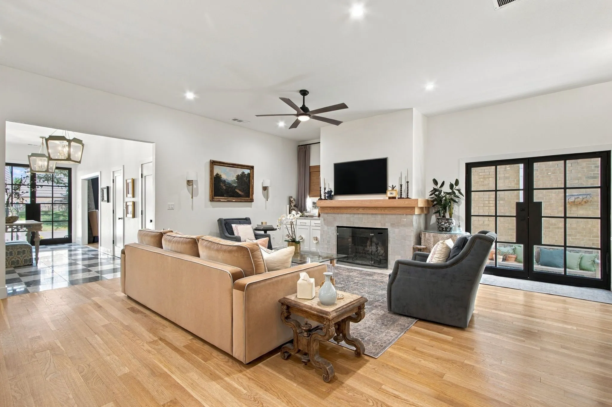 Hardwood flooring, fireplace with stone surround and wood mantel, recessed lighting, ceiling fan, and French doors