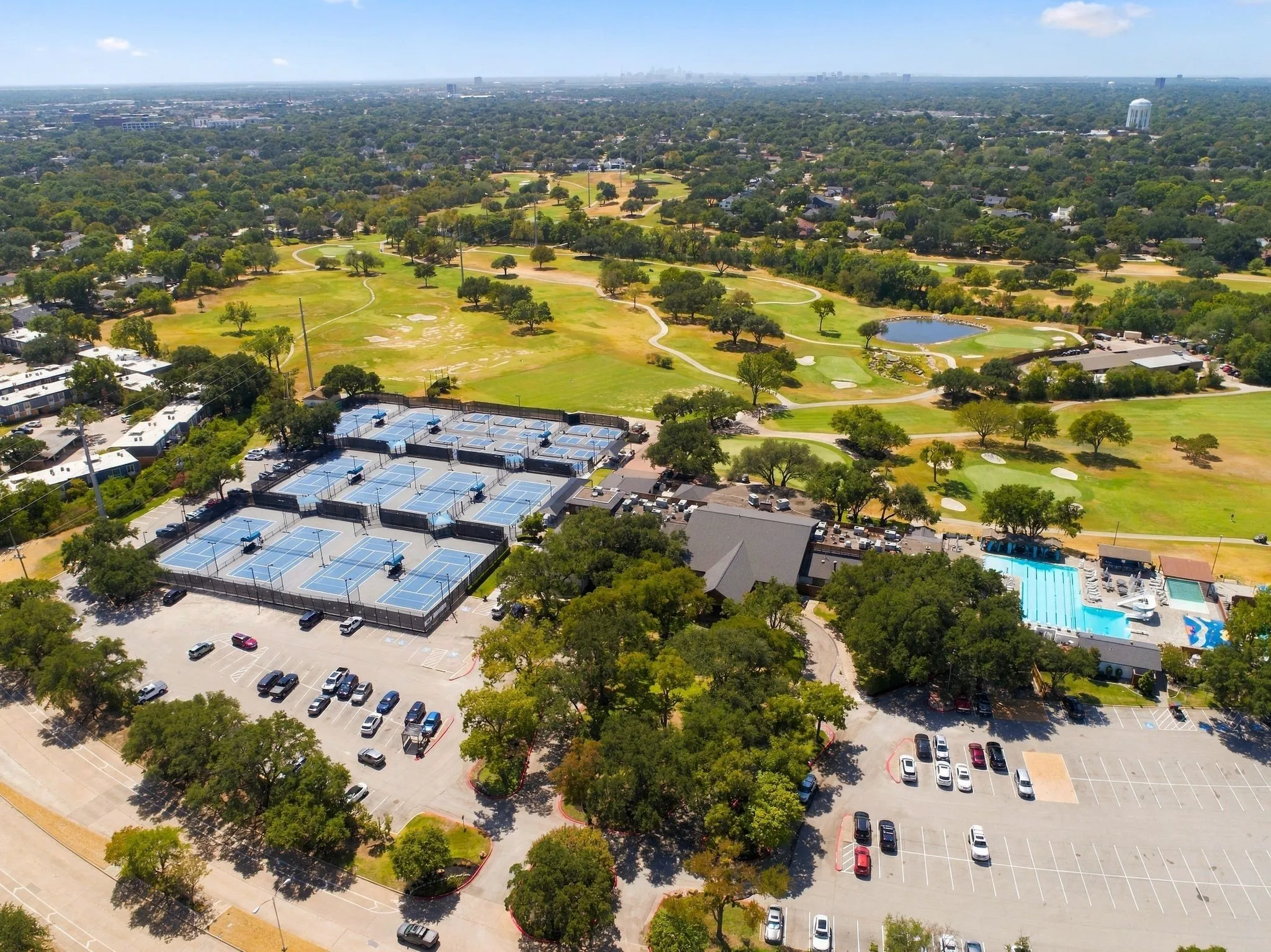 Expansive golf course with multiple greens, serene pond feature, numerous tennis courts, and a large outdoor swimming pool with dedicated lap lanes