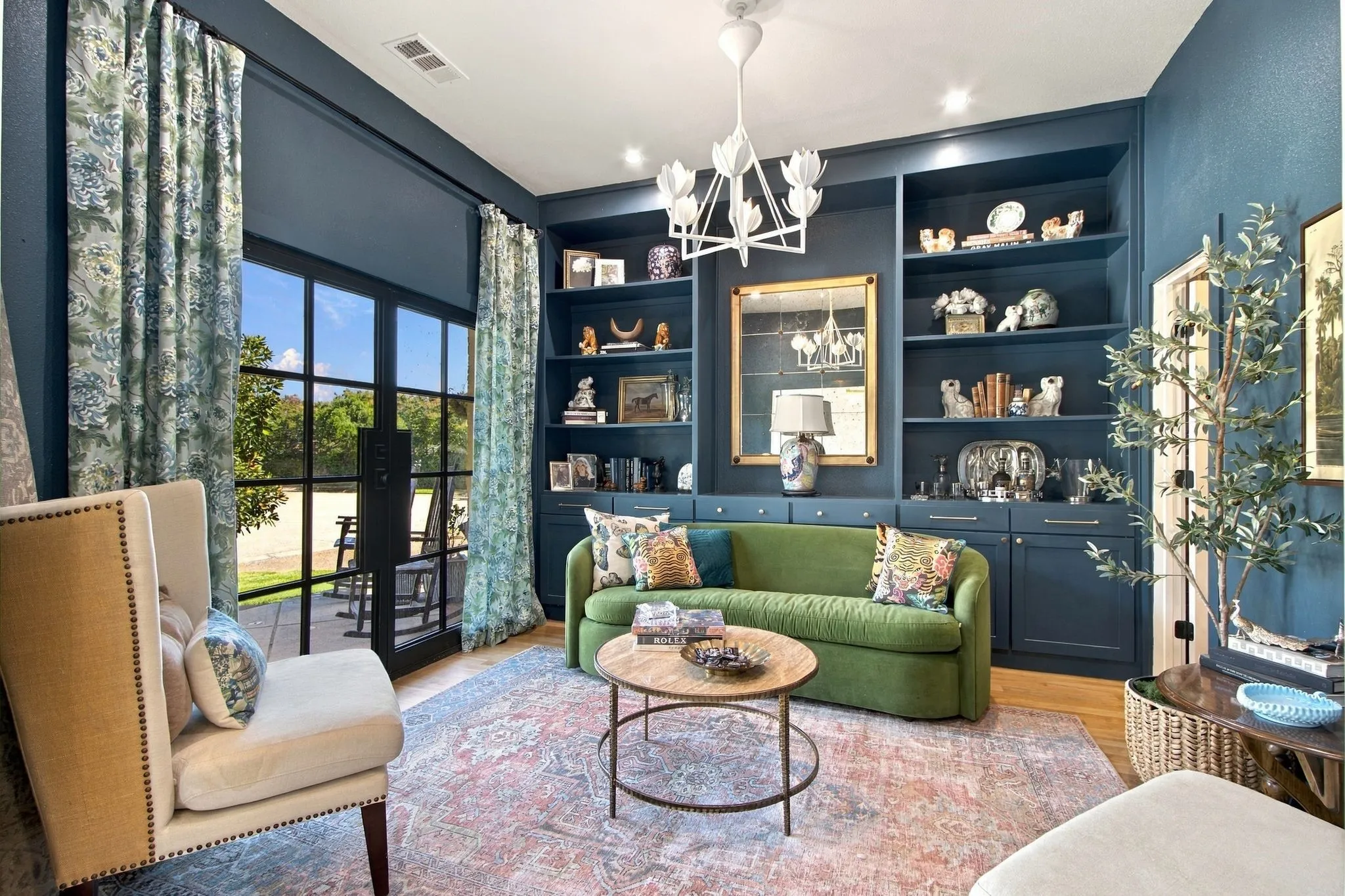 Custom built-in shelving, glass-panel French doors, wood-finish flooring, and a decorative chandelier