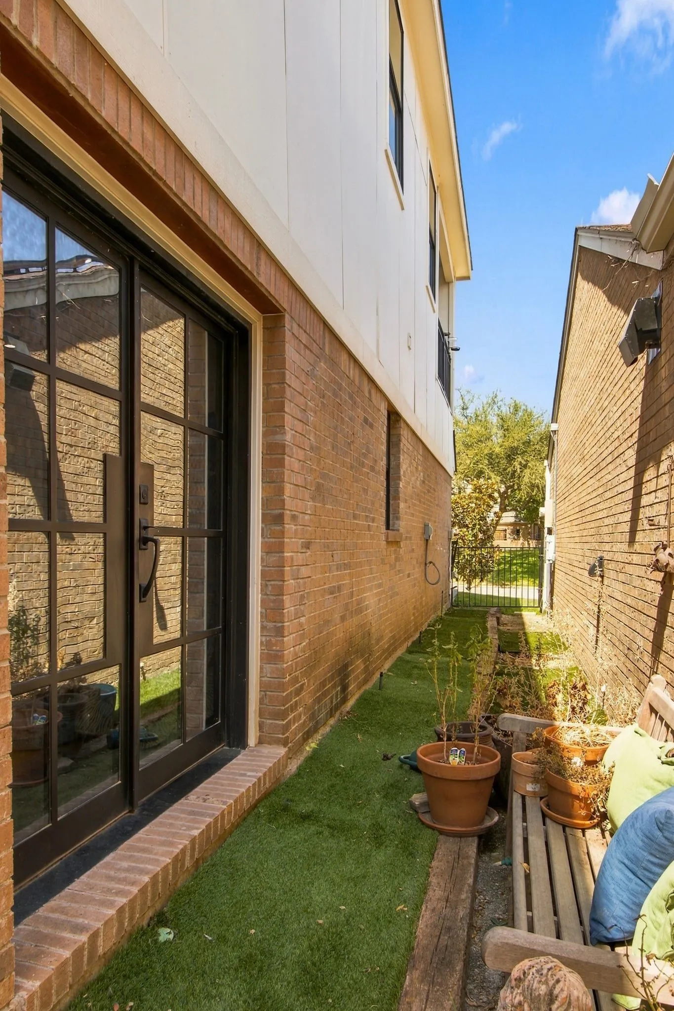 Brick and siding exterior featuring a glass-paneled entry door, a brick threshold, and artificial turf landscaping