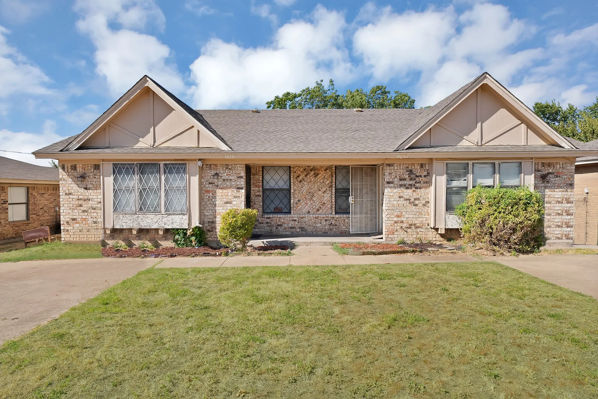 Brick exterior featuring decorative gables and a shingle roof
