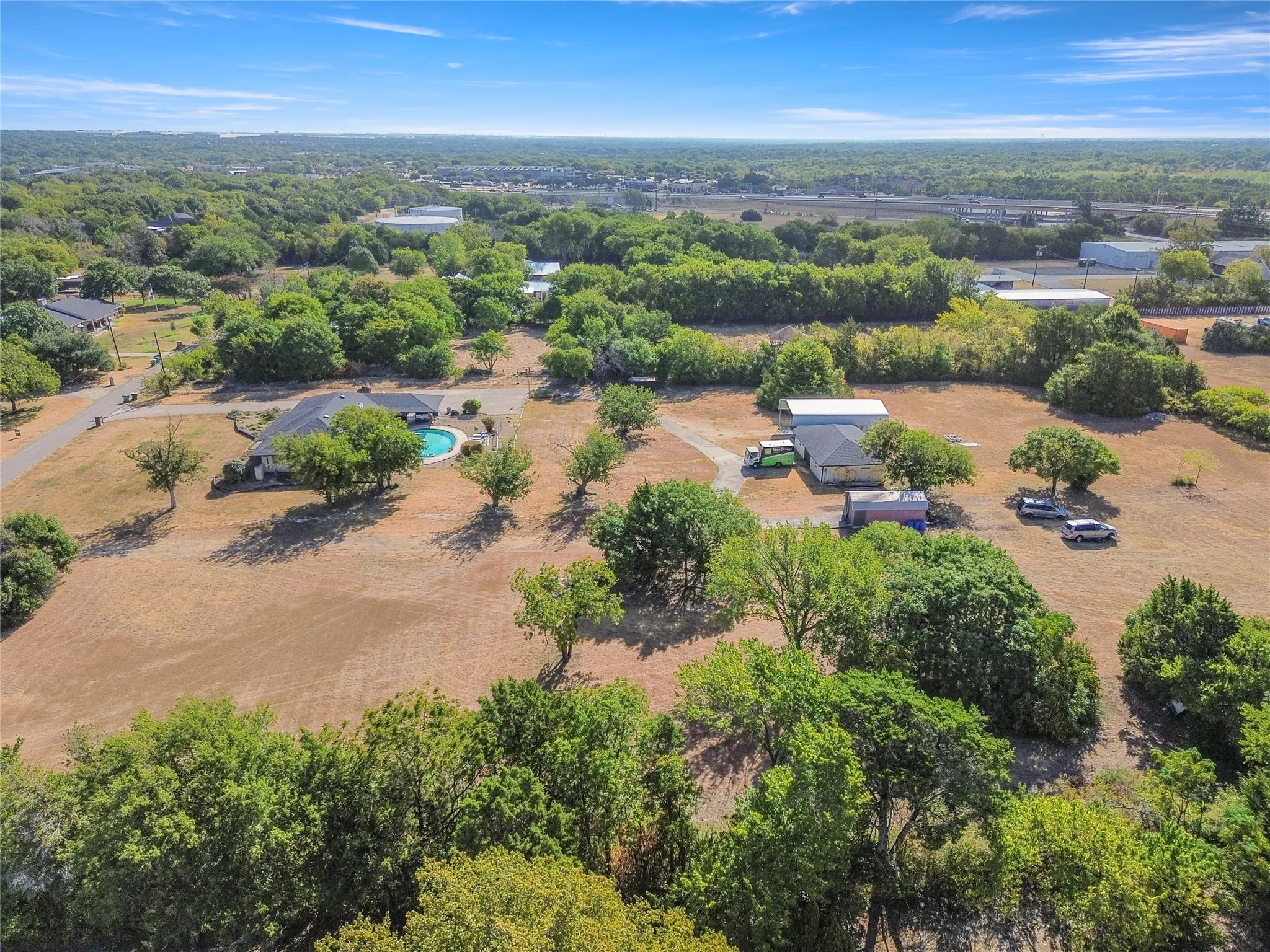 Expansive property featuring multiple structures, a private pool, and mature trees across a substantial land area