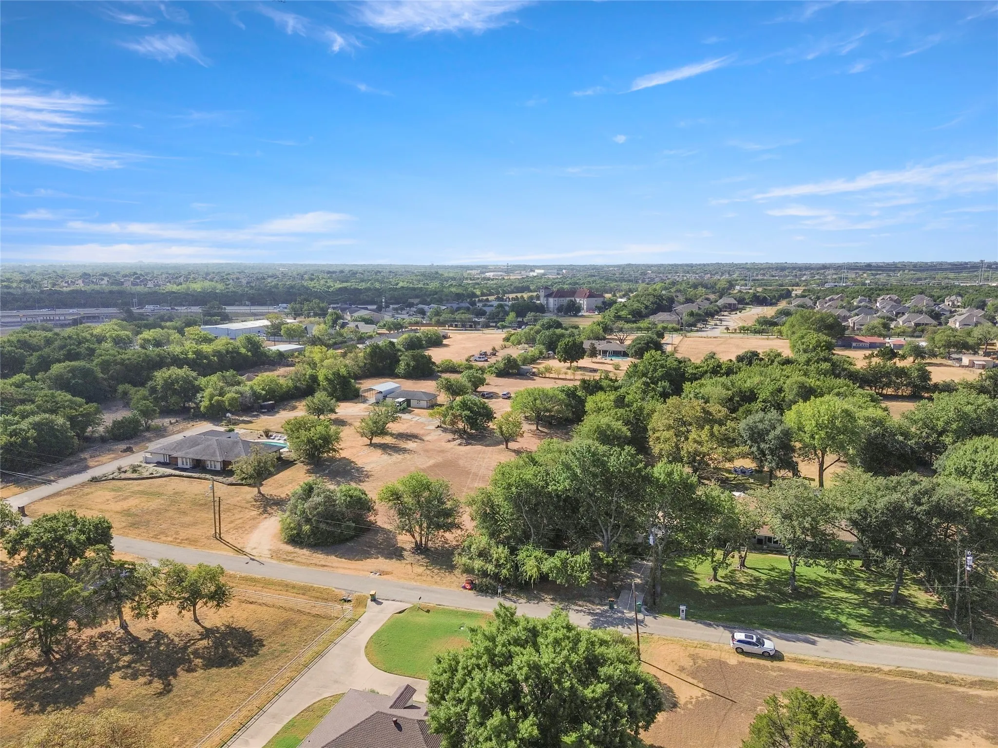 Expansive undeveloped land with scattered mature trees and residential structures
