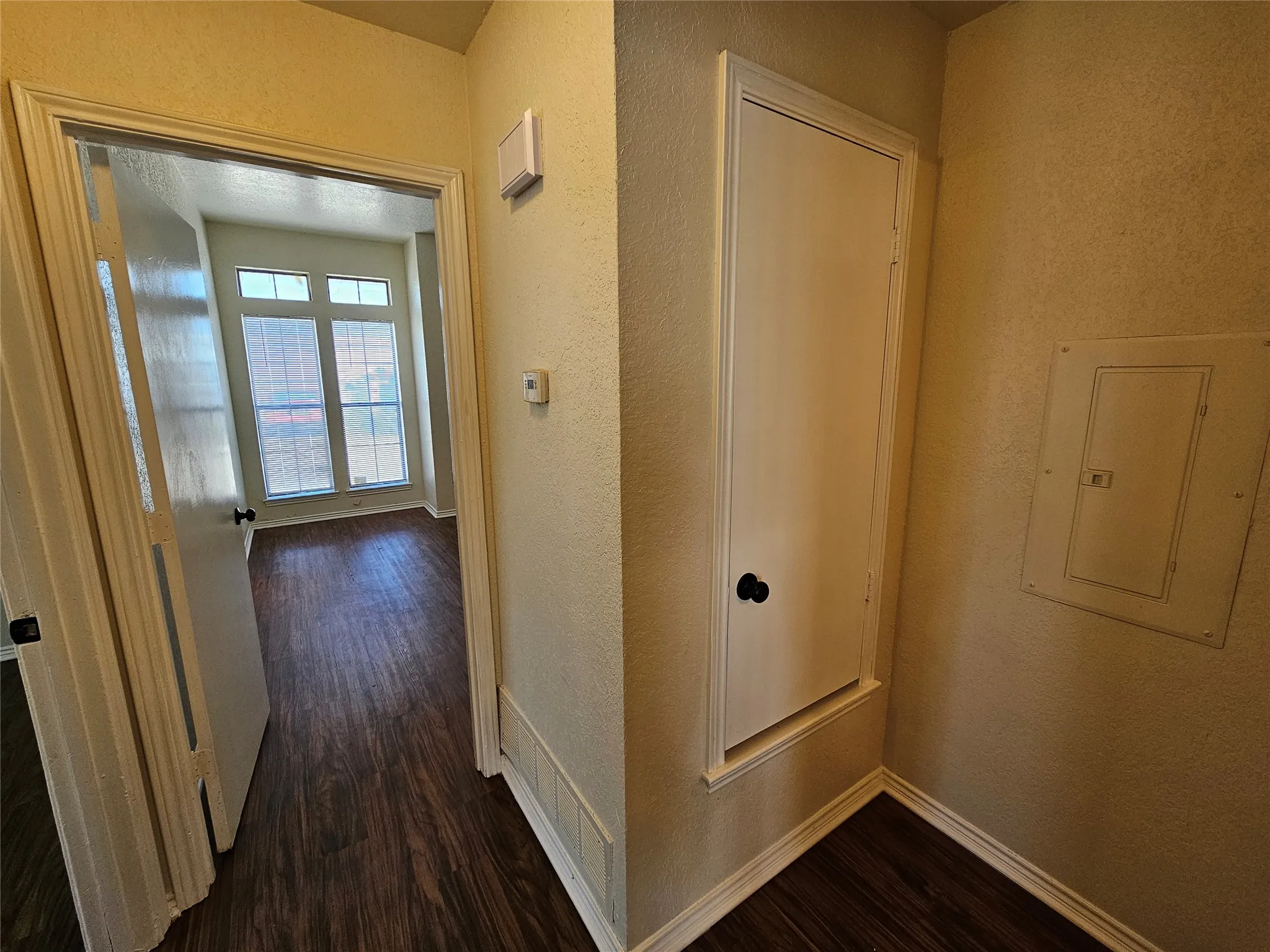 Wood-finish flooring throughout, framed doorway, and a utility access panel