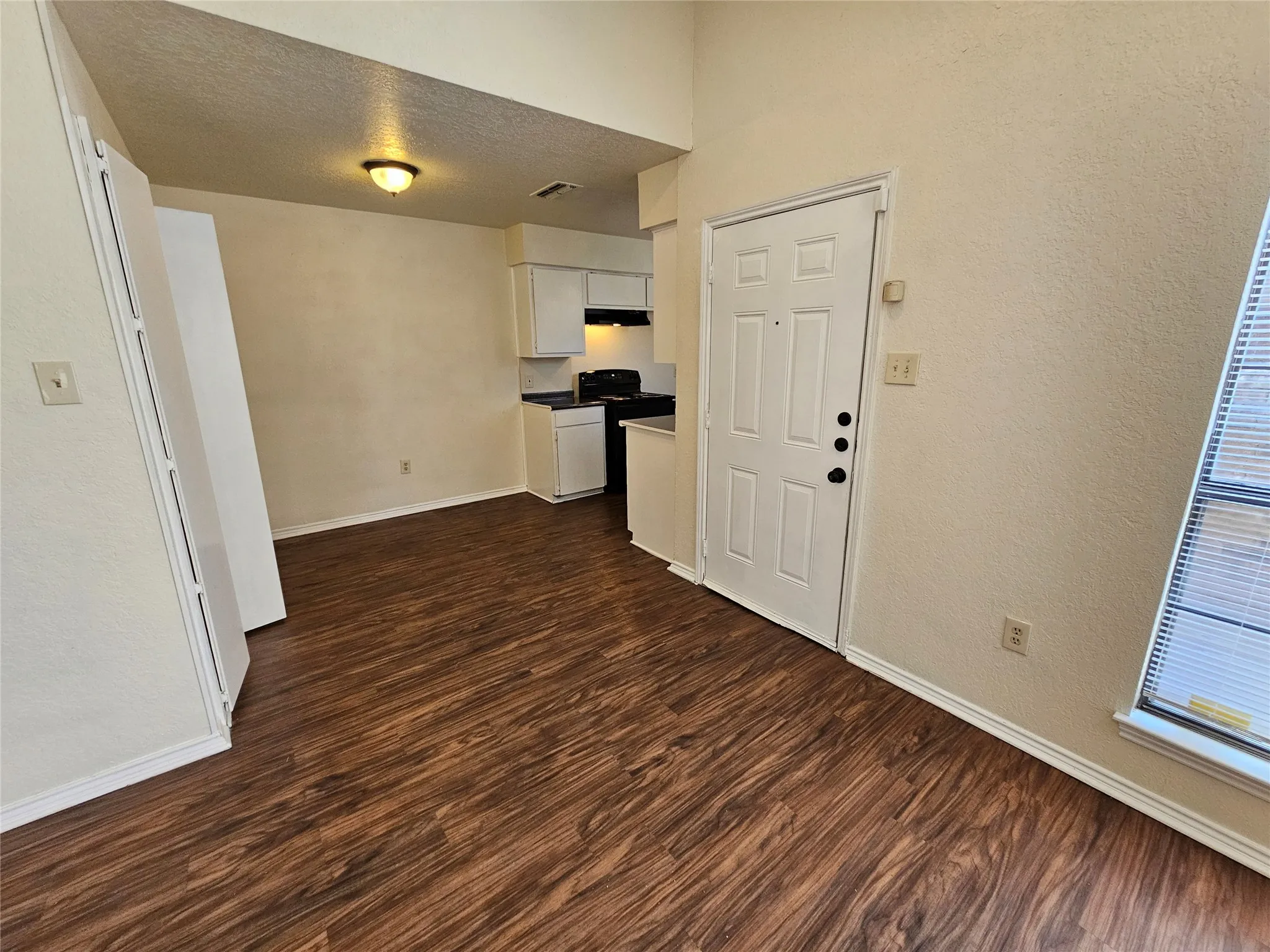 Wood-finish flooring throughout, with a window featuring horizontal blinds