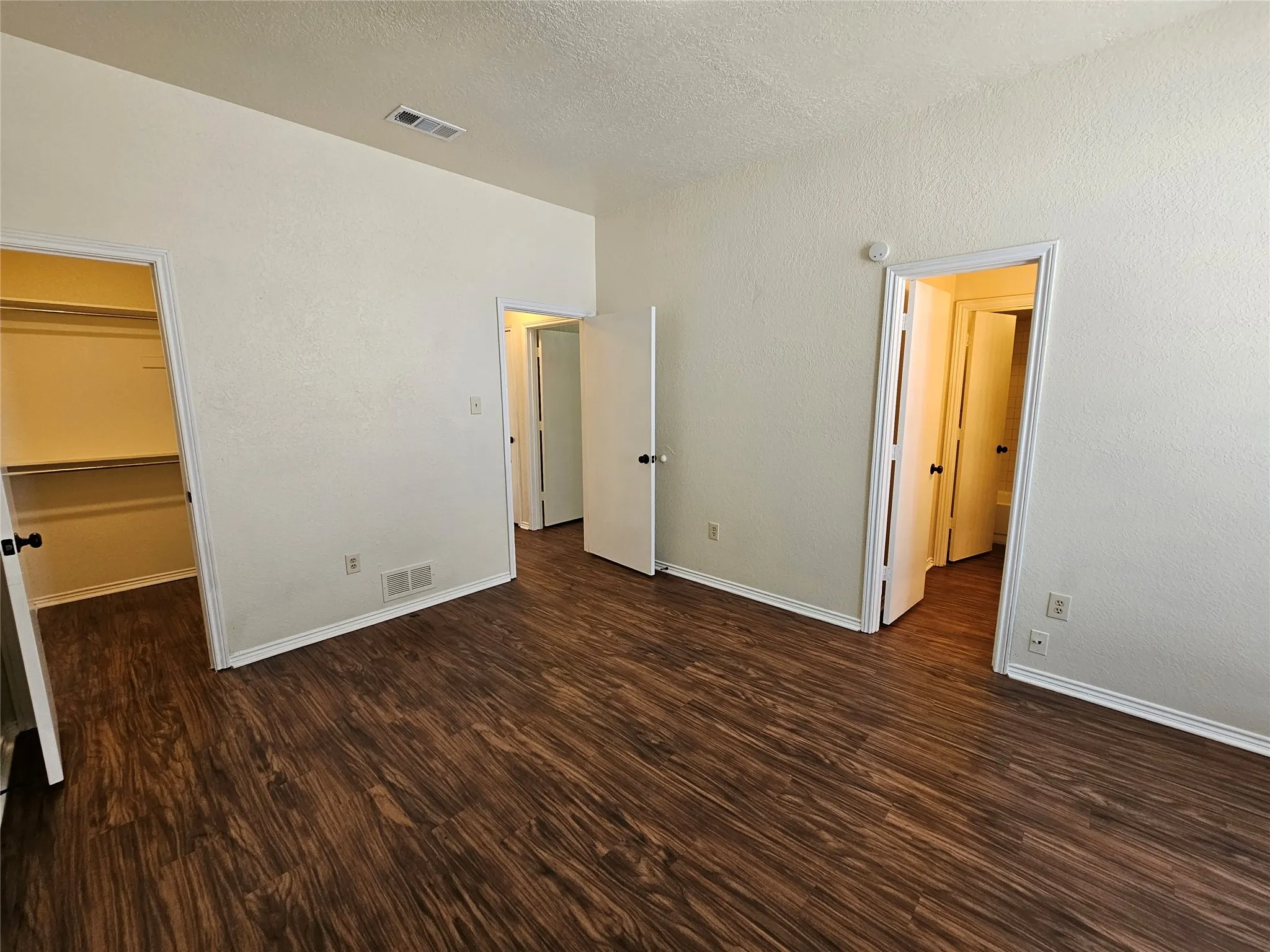 Wood-finish flooring, white baseboards, and built-in closet shelving