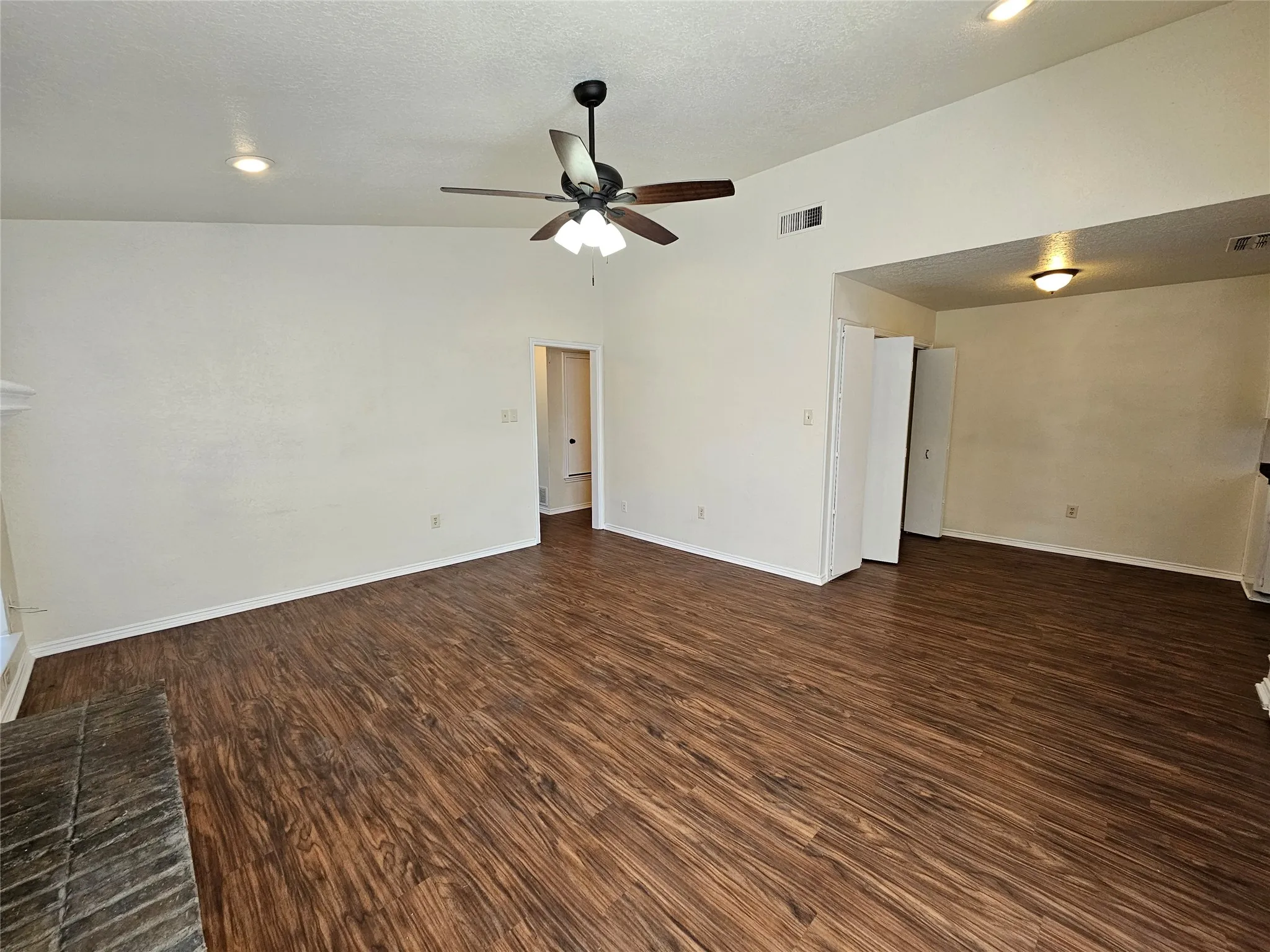 Expansive interior featuring wood-finish flooring, vaulted ceilings, and a ceiling fan with integrated lighting