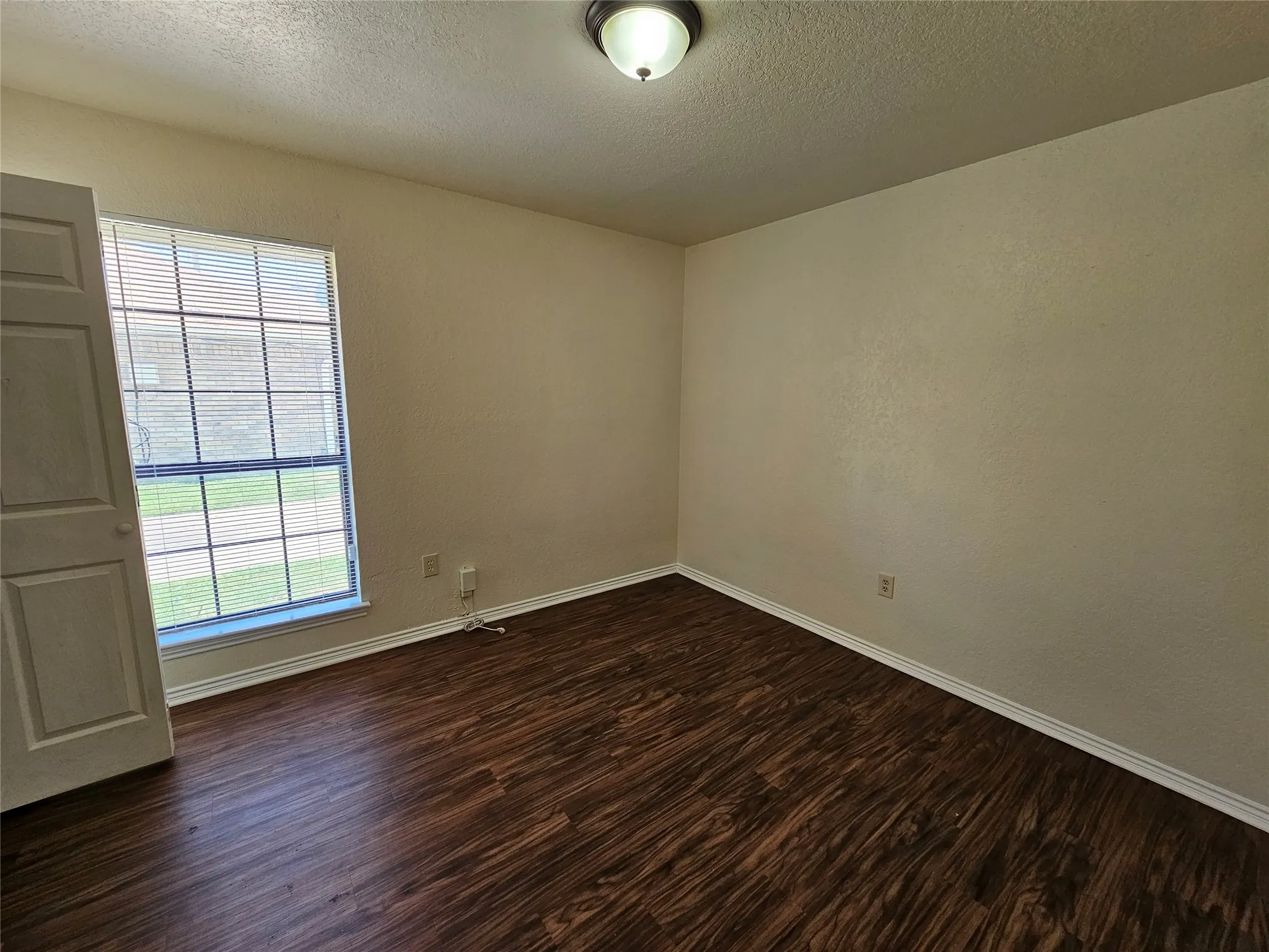 Neutral wall tones, wood-finish flooring, white trim, and a window with blinds