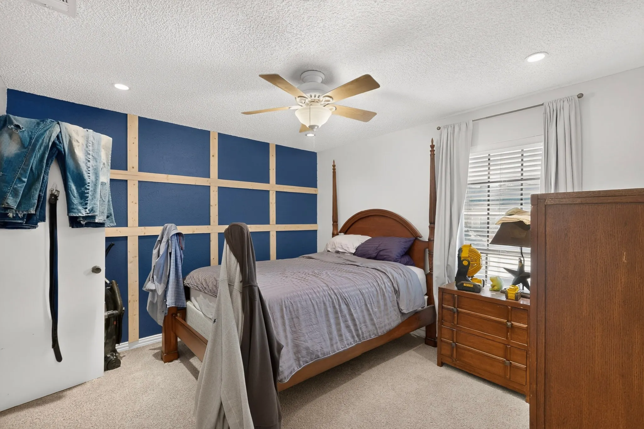 Carpet flooring, ceiling fan with light fixture, recessed lighting, window with blinds, and decorative accent wall