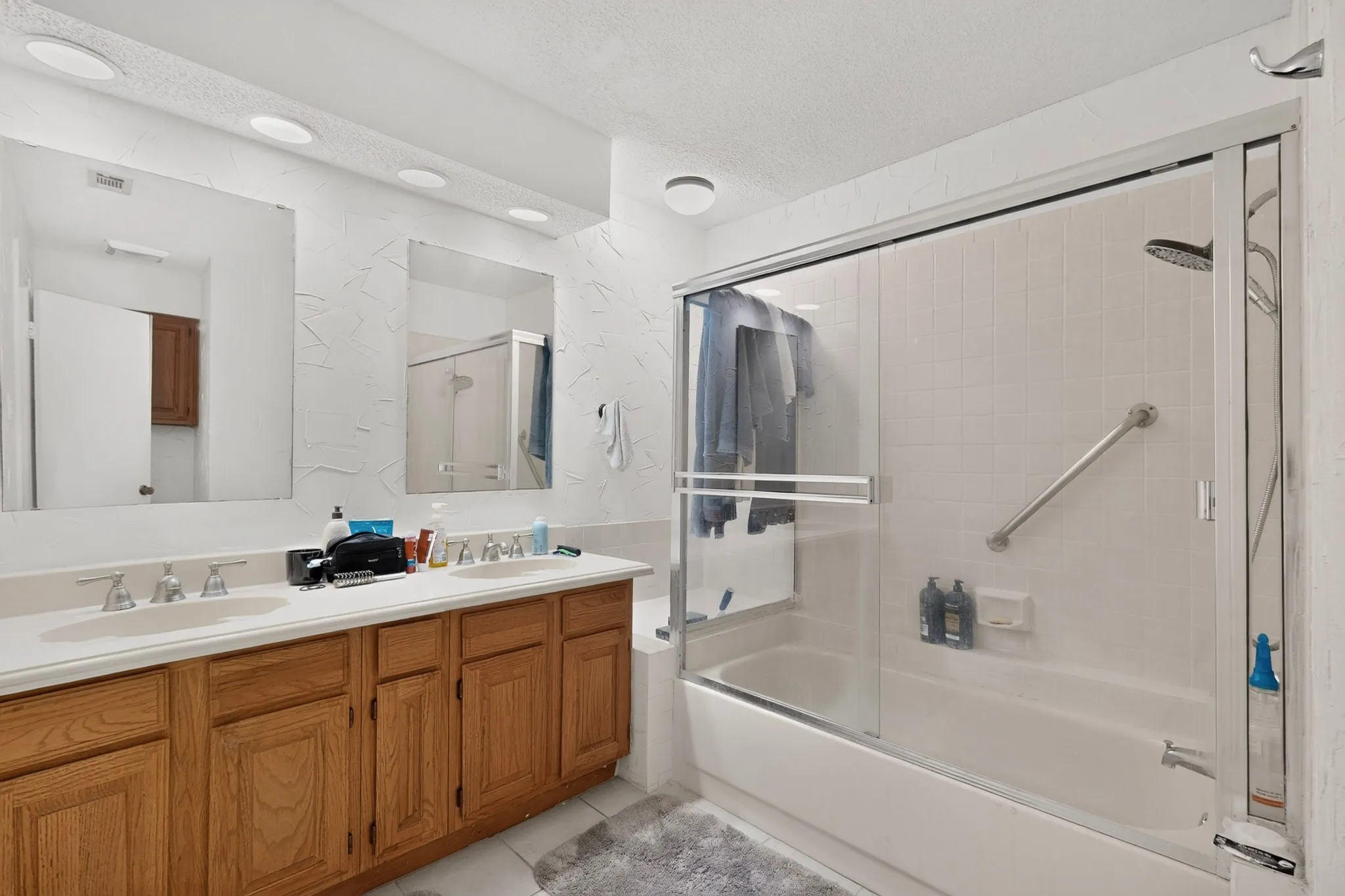 Dual vanity with integrated sinks and wood-finish cabinetry, illuminated by recessed lighting