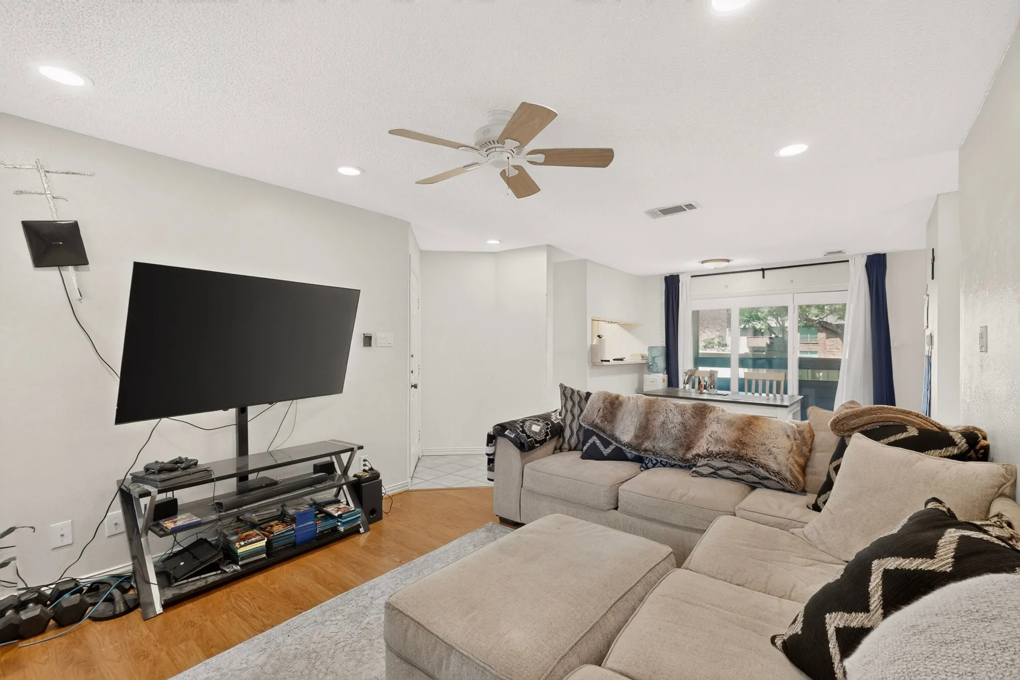 Recessed ceiling lighting, wood-finish flooring, ceiling fan with light fixture, and sliding glass doors