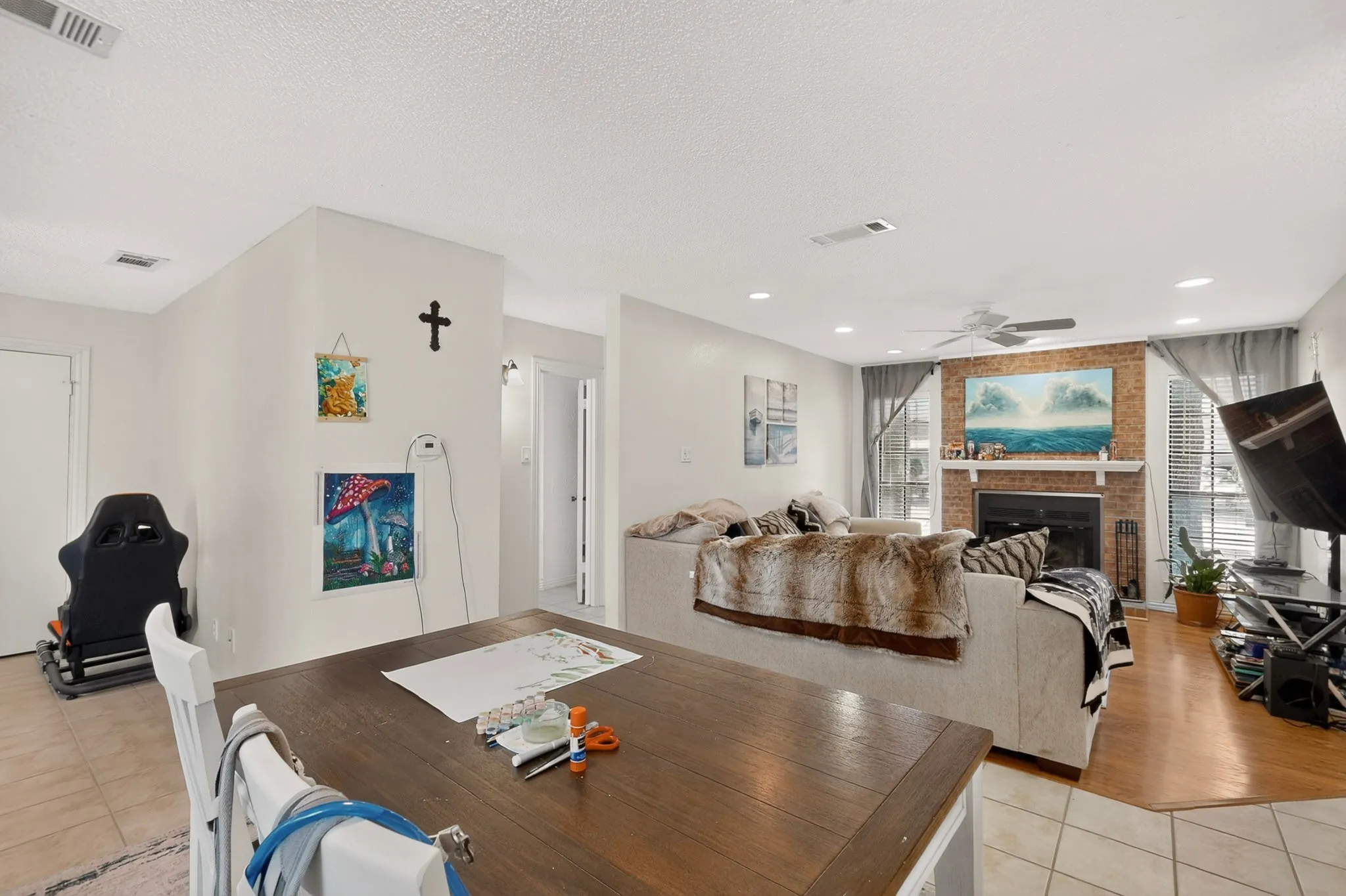 Brick fireplace with white mantel, ceiling fan, recessed lighting, and tile flooring