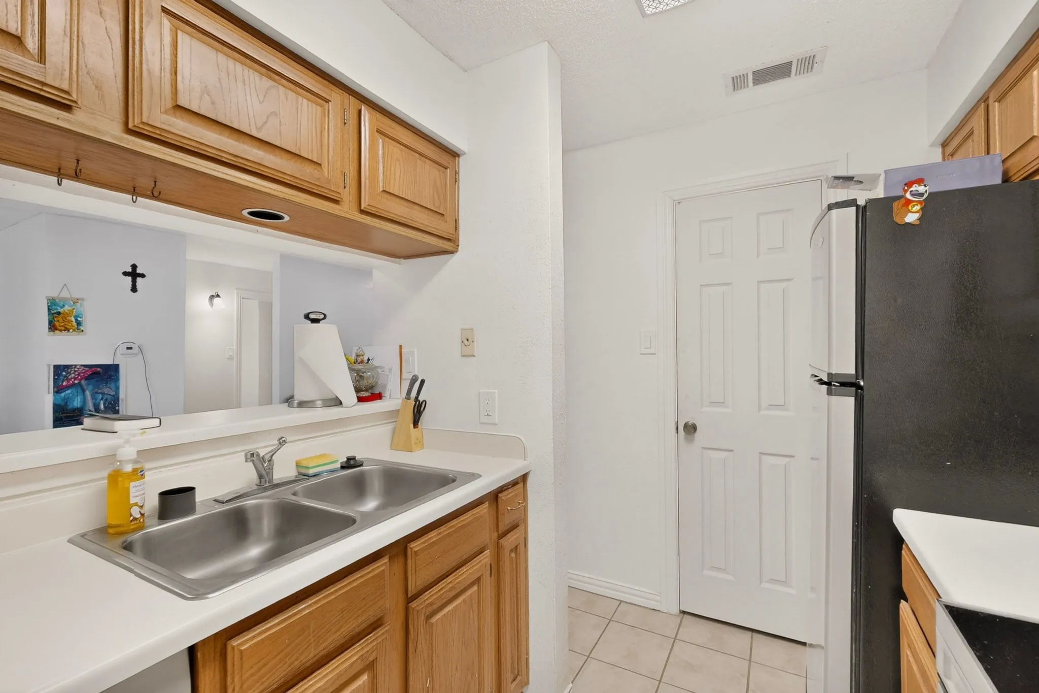 Kitchen featuring light wood-finish cabinetry, a dual basin stainless steel sink, and white countertops
