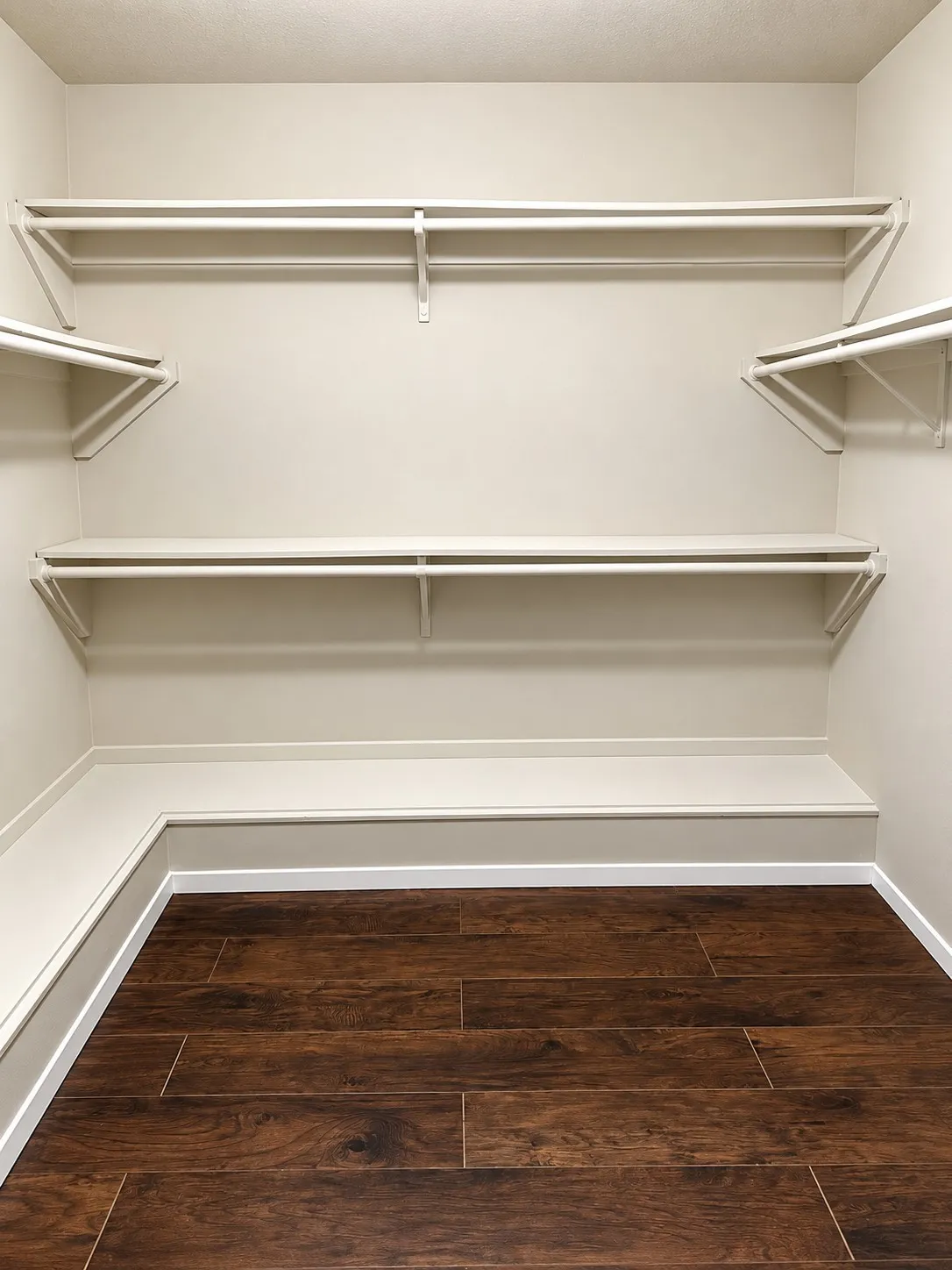 201- Primary closet system with multiple shelving units, garment rods, and wood-finish flooring