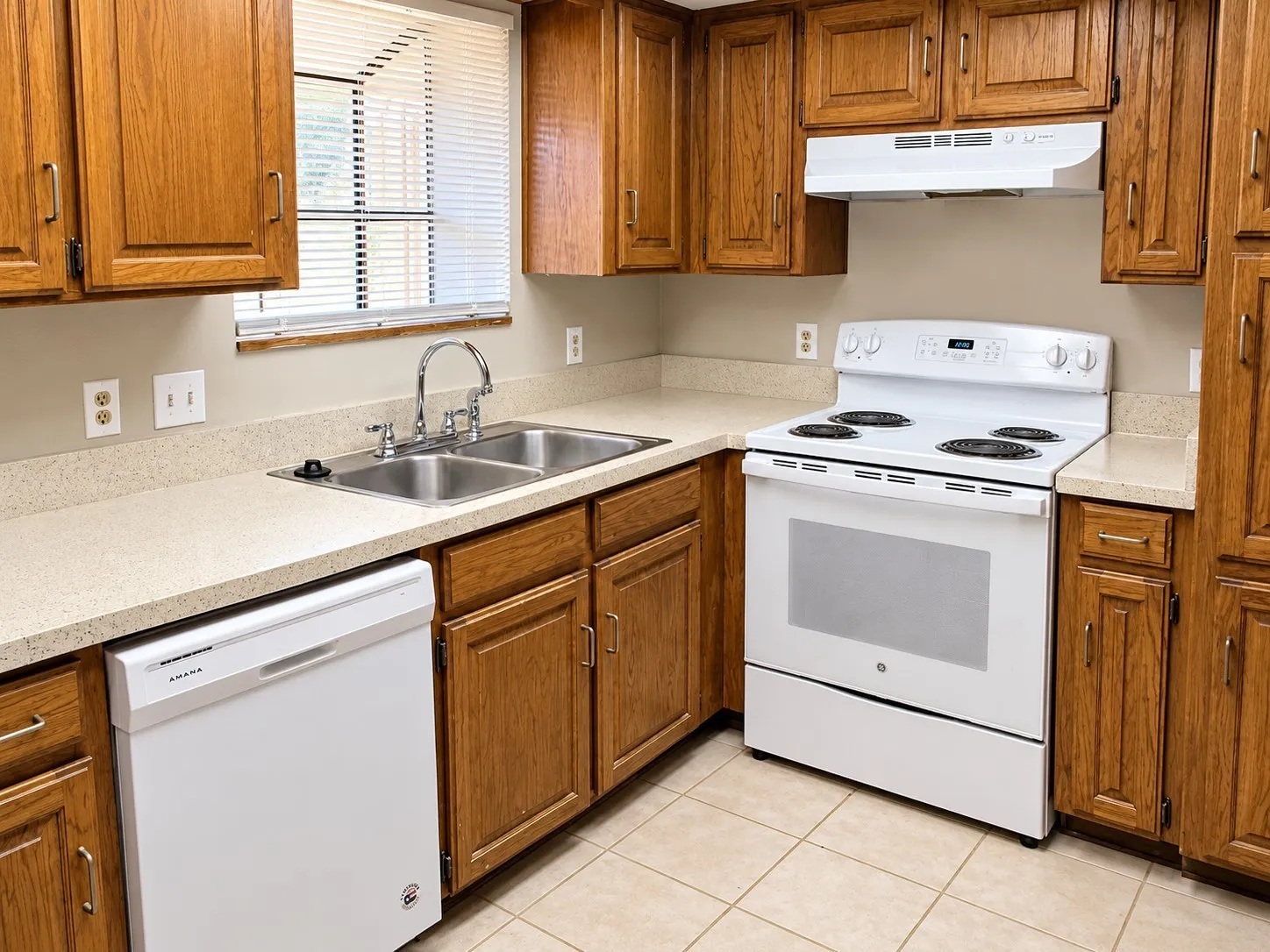 201- Wood cabinetry, light-toned countertops, tile flooring, stainless steel double basin sink, and a white electric range
