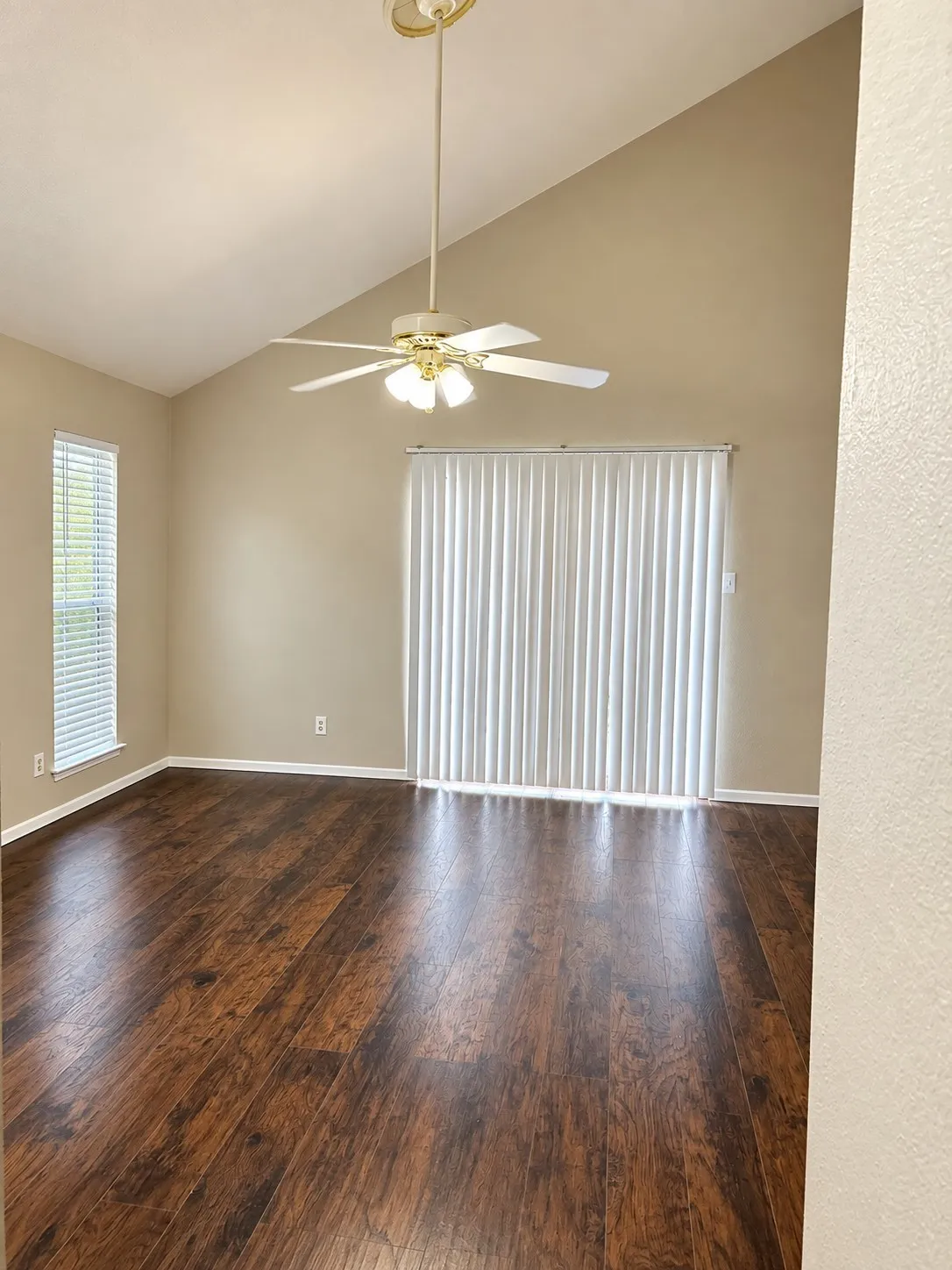 201- Vaulted ceiling with a ceiling fan, wood-finish flooring, and vertical blinds