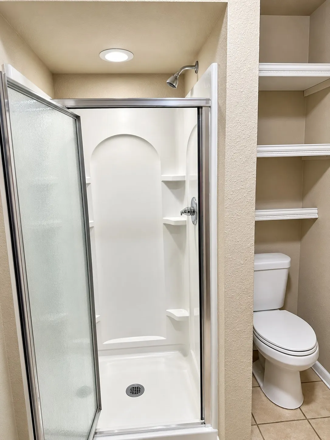 201- Walk-in shower with a glass enclosure, an integrated shower system, and recessed lighting