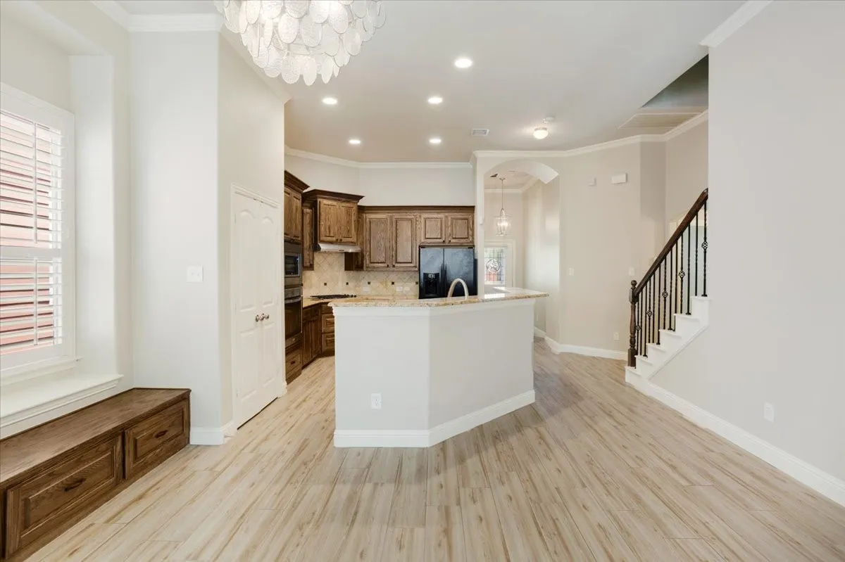 Wood-finish flooring, built-in window seating with storage, and a kitchen featuring dark wood cabinetry and a peninsula with a light-toned countertop