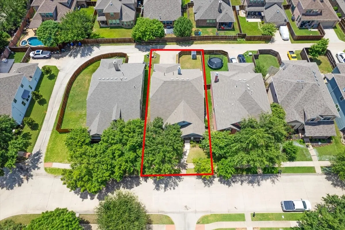 Aerial perspective highlighting the property boundaries, surrounding residences, and a paved street