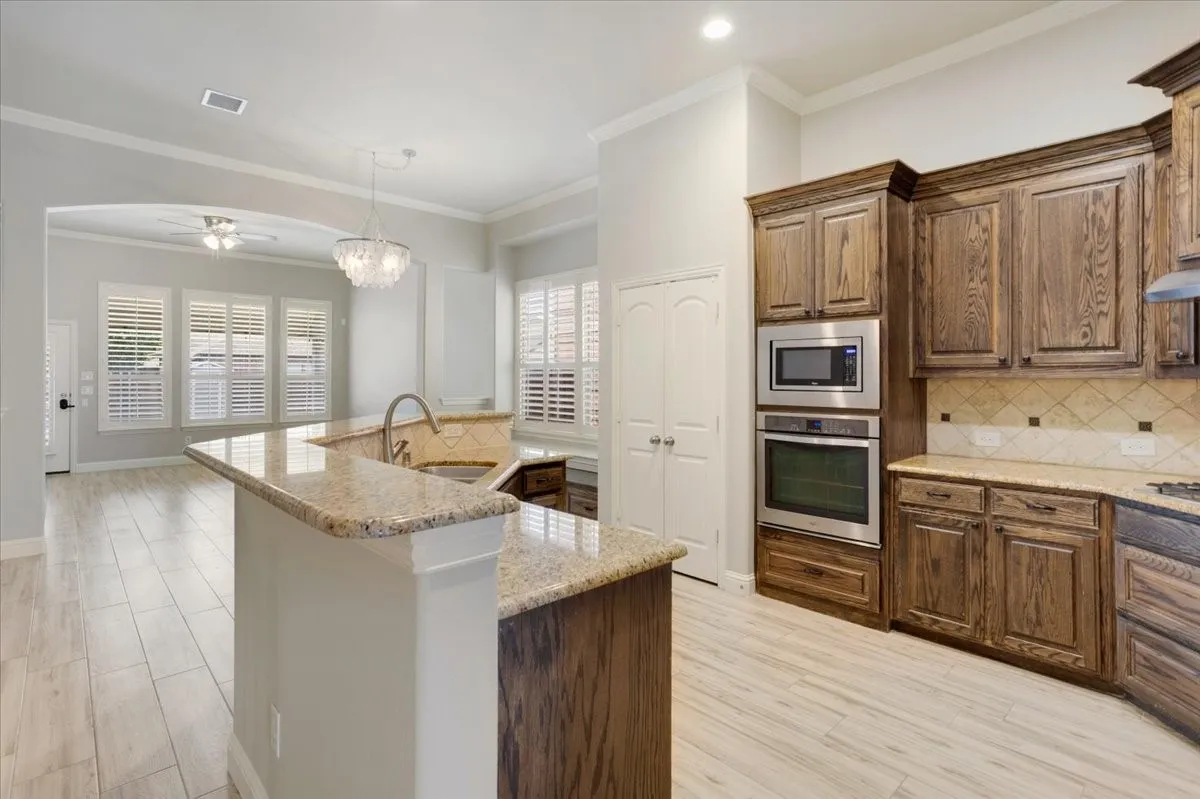 Kitchen featuring wood-finish cabinetry, stainless steel built-in appliances, a breakfast bar, and light-toned tile flooring