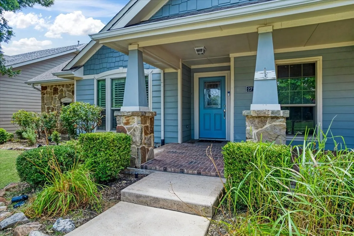 Stone and siding exterior with a covered entry, brick-patterned porch, and a vibrant blue entry door