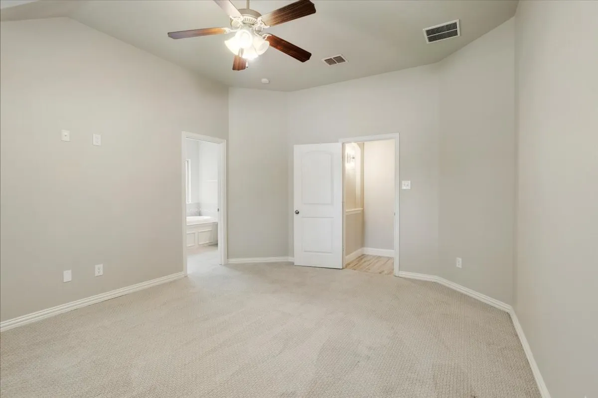 Vaulted ceiling with a ceiling fan, light-toned carpeting, and two doorways