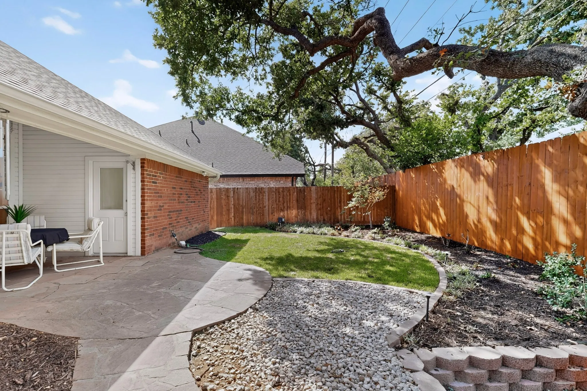 Private backyard featuring a flagstone patio, manicured lawn, and wood privacy fencing