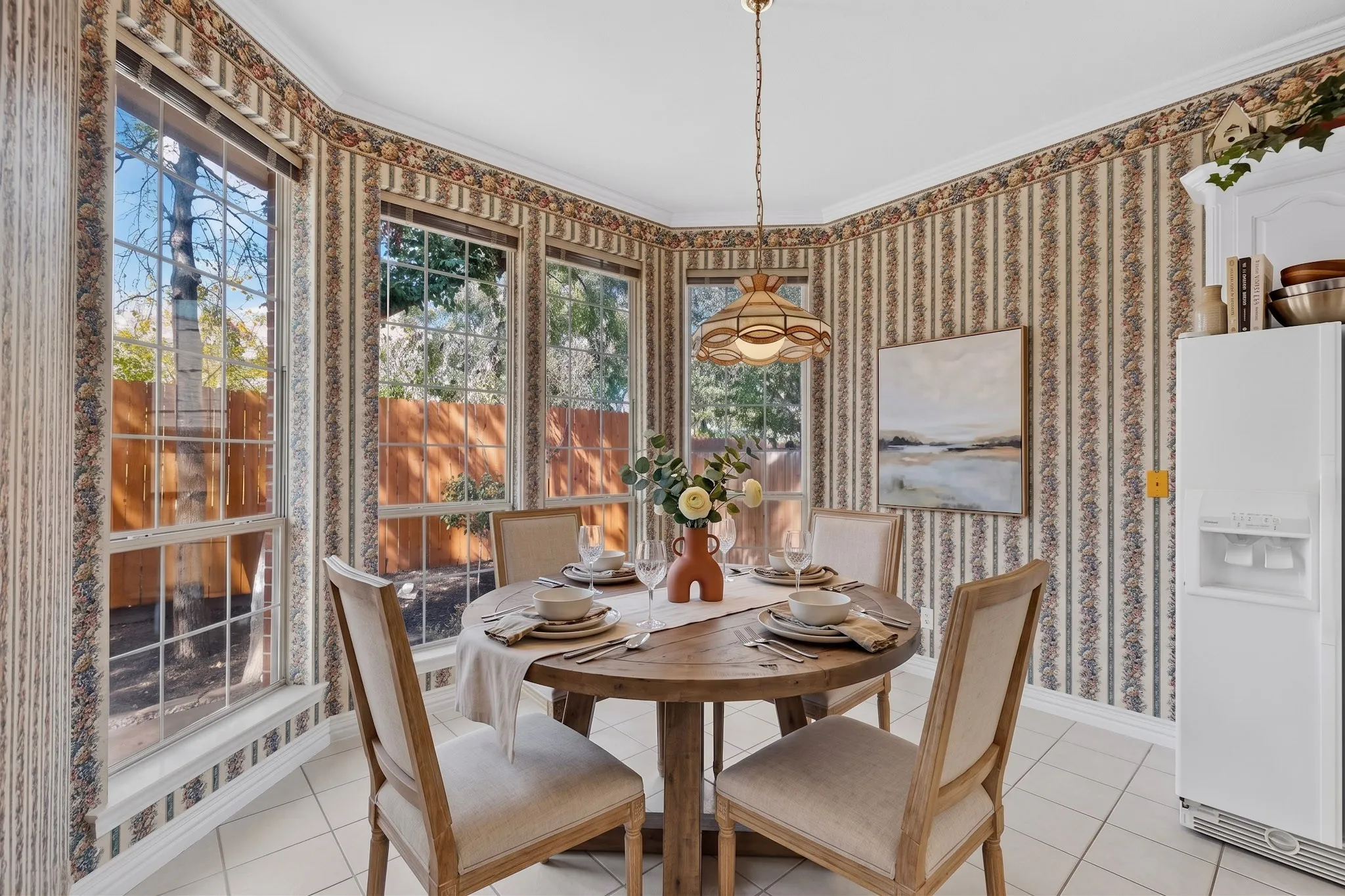Bay window with multiple panes, crown molding, ceiling-mounted light fixture, tiled flooring, and built-in white cabinetry