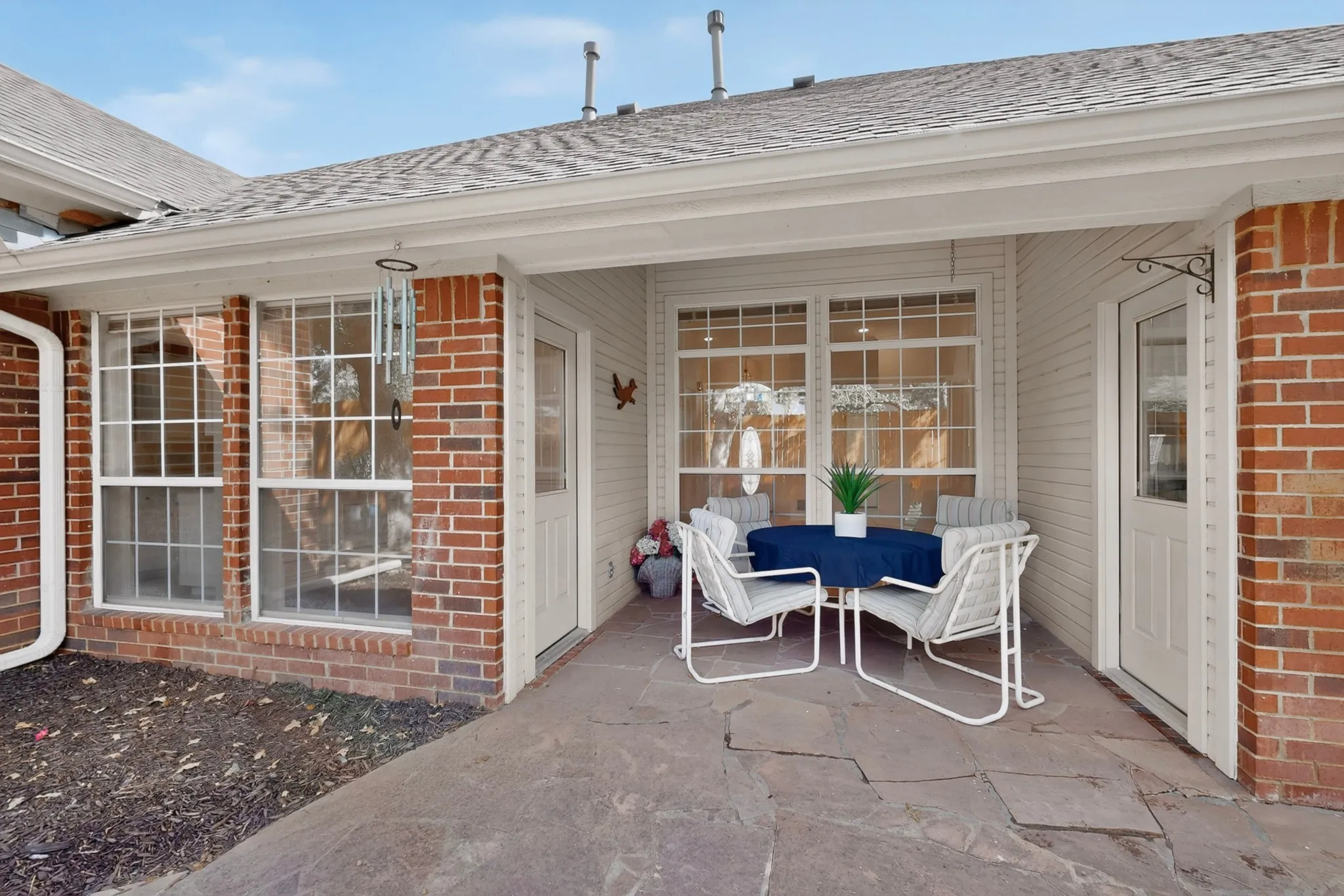 Covered patio with stone flooring, brick exterior, and multiple pane windows