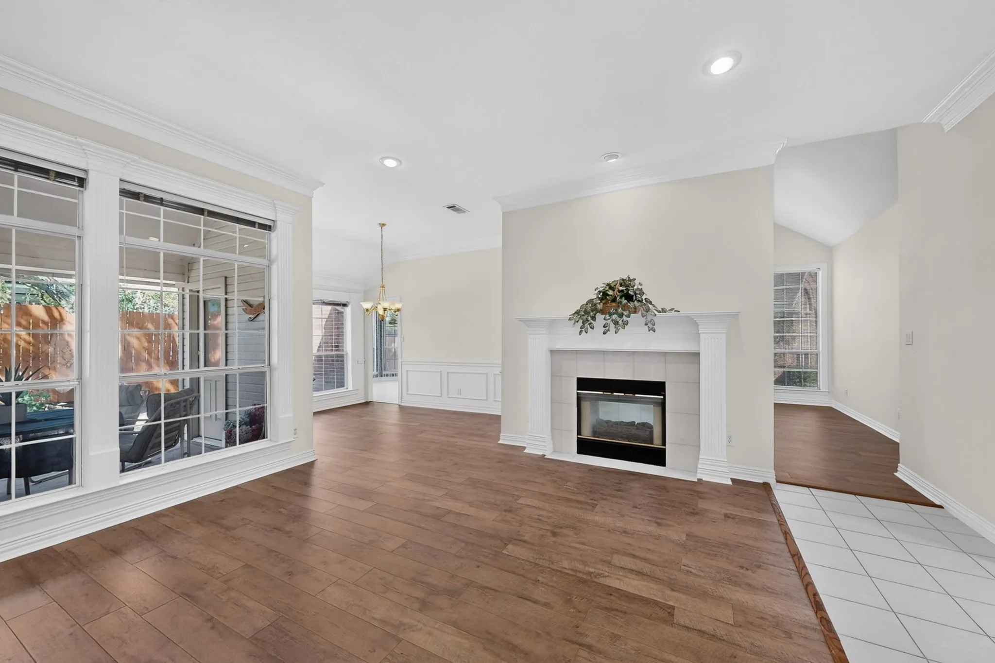 Wood-finish flooring throughout, a gas fireplace with a tiled surround, and large windows with grid patterns
