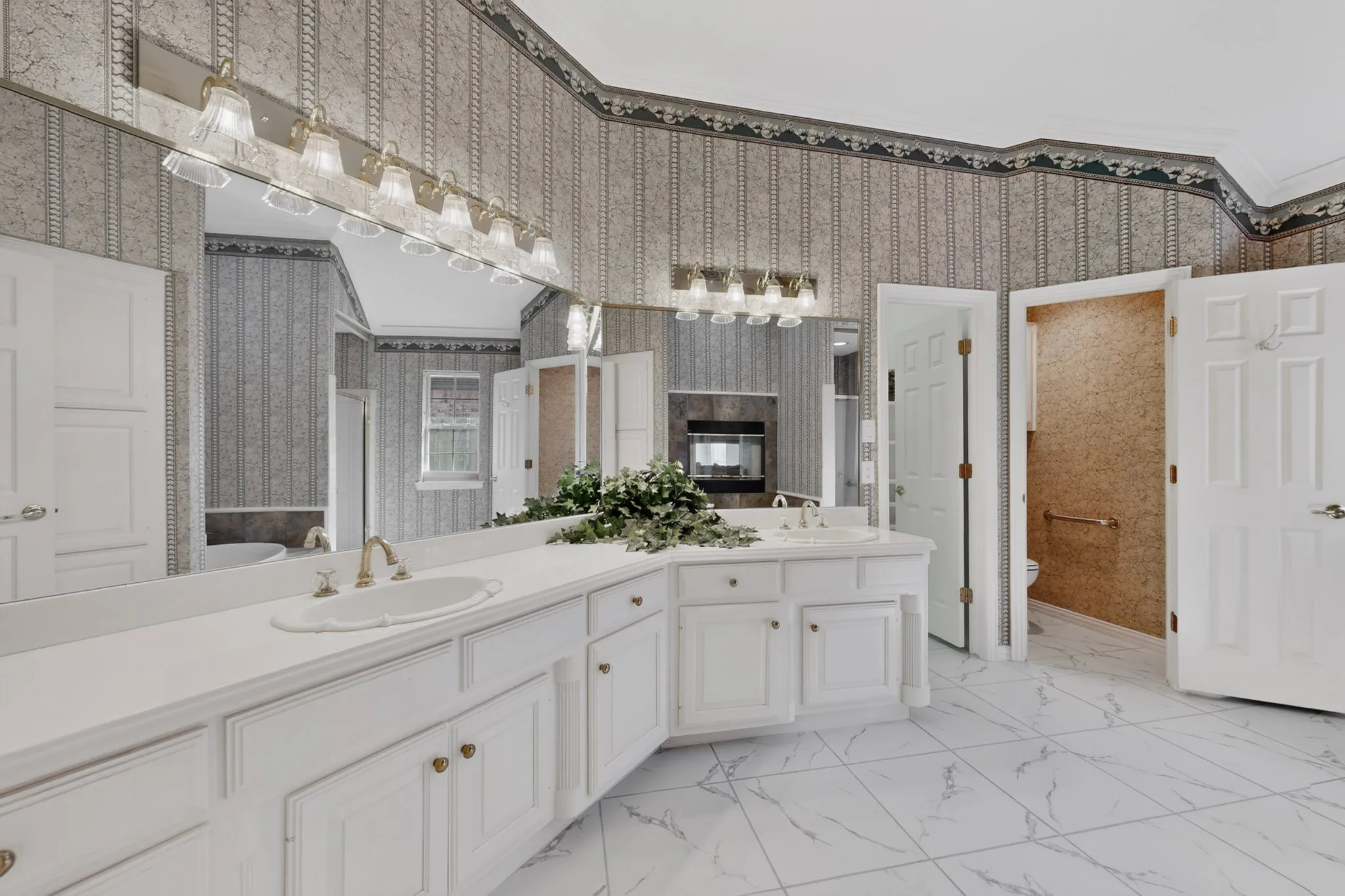 Dual vanity with white cabinetry and integrated sinks, oversized wall mirror, and tiled flooring